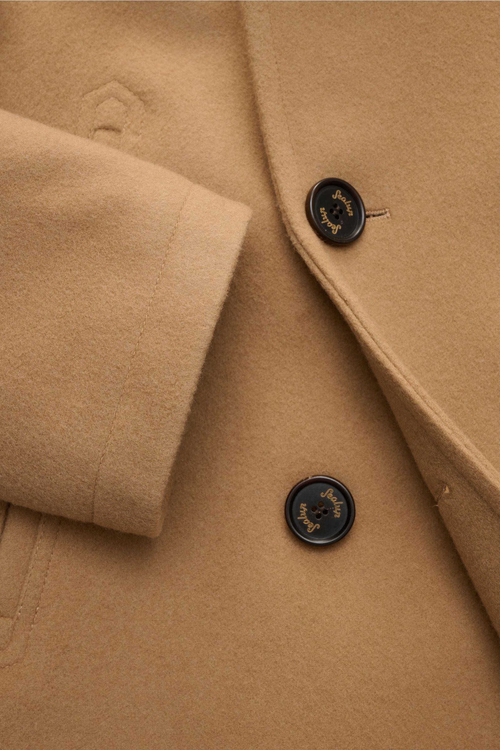 Nahaufnahme der Sealup Cabanjacke 'Amalfi Peacoat' camel aus weichem Wolle-Cashmere-Mix, Slim Fit, breitem Reverskragen, zweireihiger Drei-Knopf-Leiste, schrägen Leistentaschen und kleinem Metall-Logo, leichte Wattierung sichtbar.