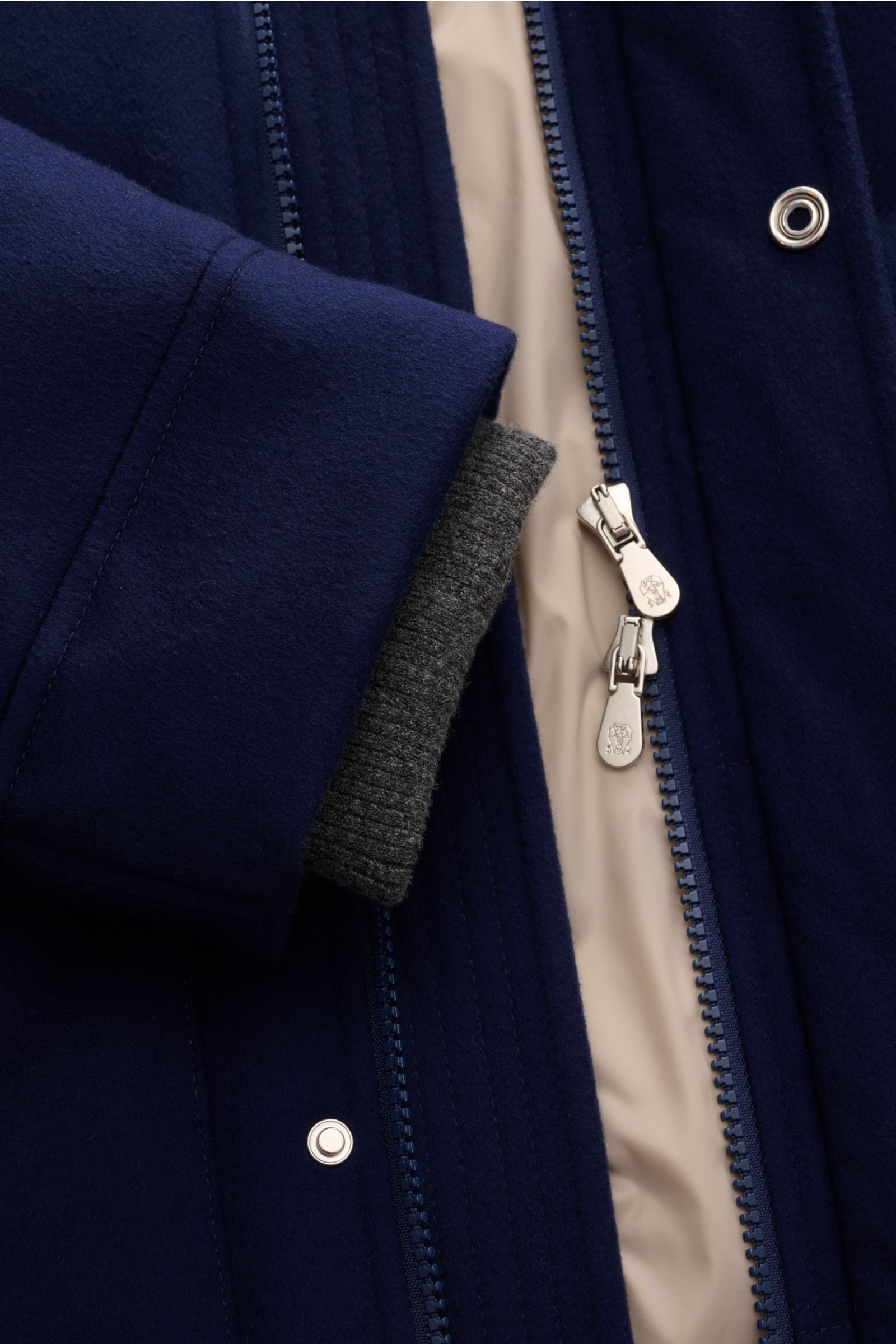 Nahaufnahme der dunkelblauen Brunello Cucinelli Daunenjacke aus reiner Wolle mit zwei-Wege-Reißverschluss, Rippstrick-Innenbündchen und Kontrastfutter.