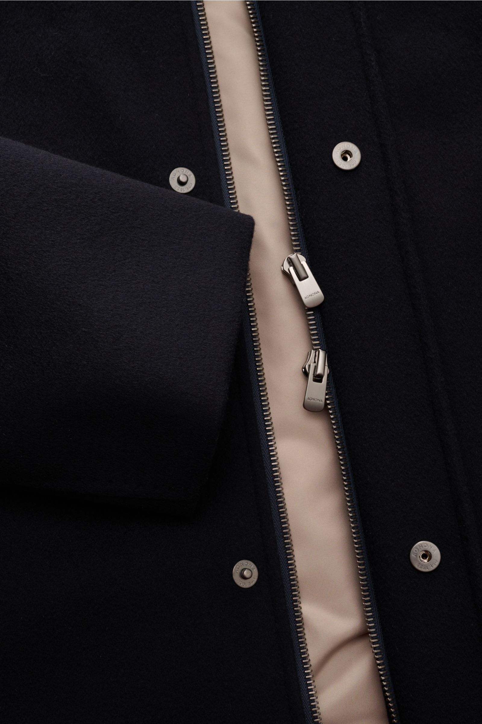 Nahaufnahme der Agnona Cashmere Jacke navy von schräg oben, zeigt reinen Cashmere, weichen Griff, leichte Wattierung, Slim Fit, Fünf-Knopf-Leiste, Zwei-Wege-Reißverschluss mit Metall-Emblem, Windblende mit Druckknöpfen und geschmeidiges Futter.