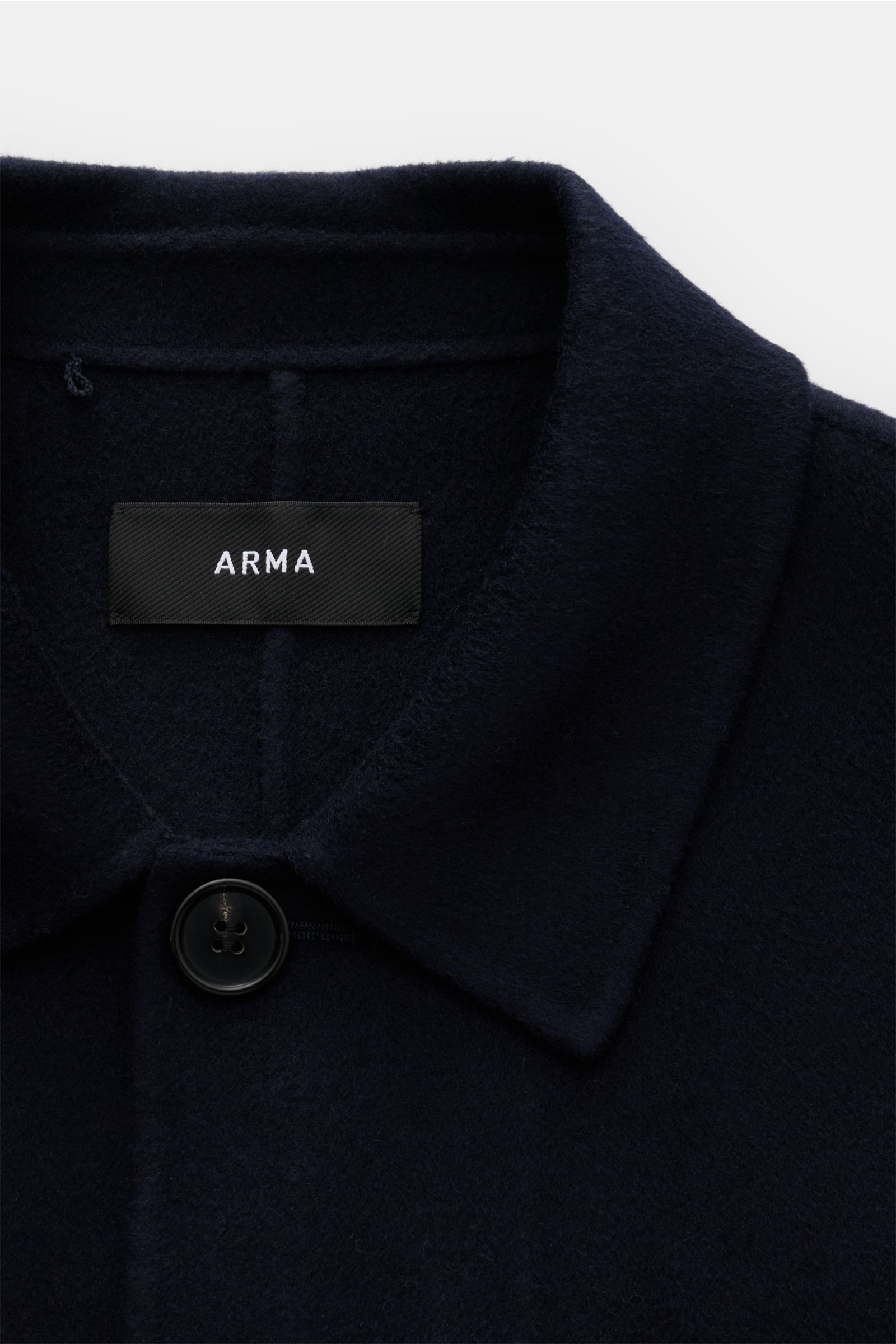 Close-up front view of the Arma Overshirt 'Jur' navy showing the collar, top button, and black ARMA label on soft pure wool fabric. 

Mit seinem klaren Schnitt und dem hochwertigen Wollstoff bringt das Overshirt 'Jur' von ARMA natürliche Eleganz in die