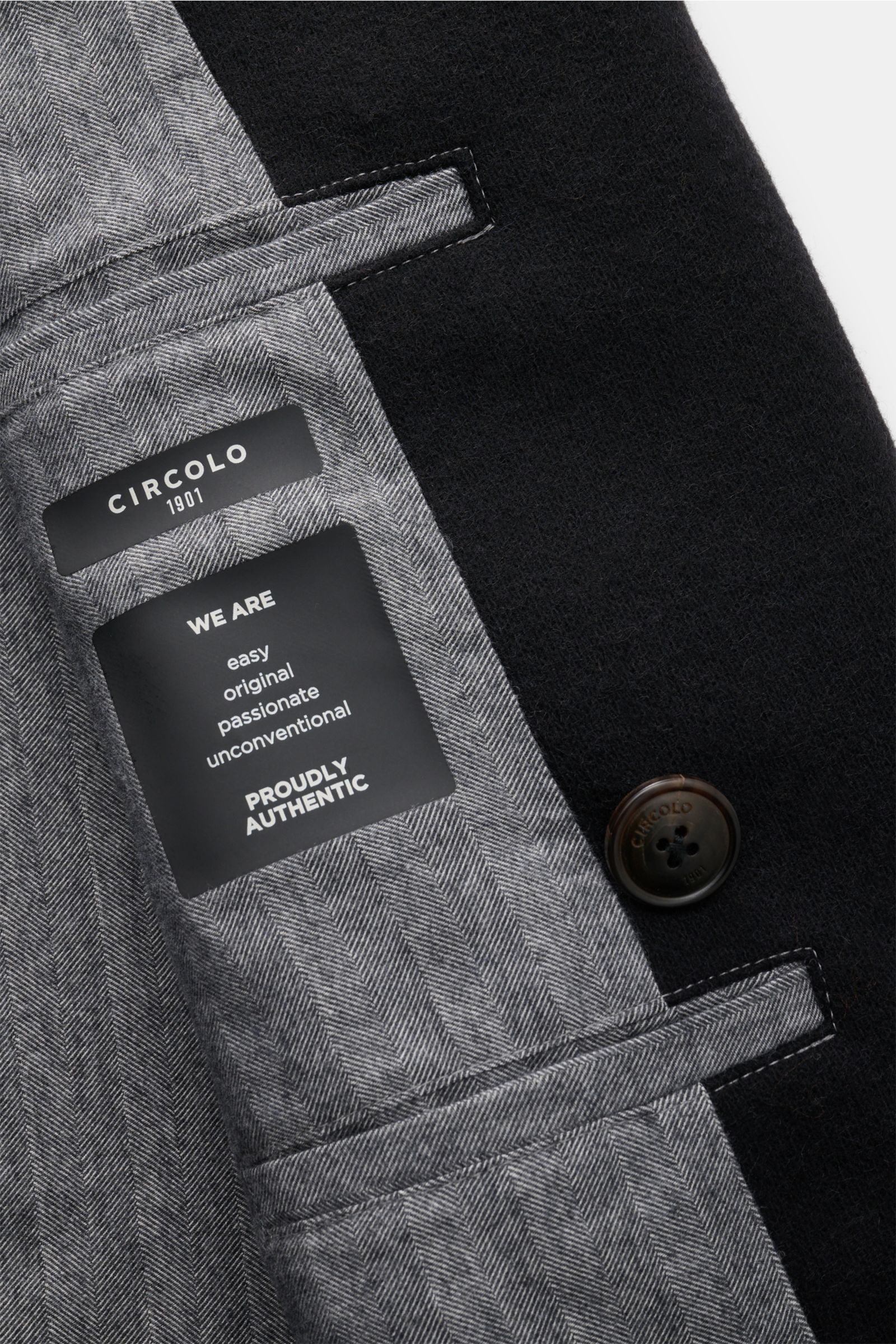 Nahaufnahme der Innenseite der Circolo 1901 Cabanjacke schwarz, zeigt gewalkte Strick-Qualität, Baumwollfutter, Innentaschen und Markenlabel.