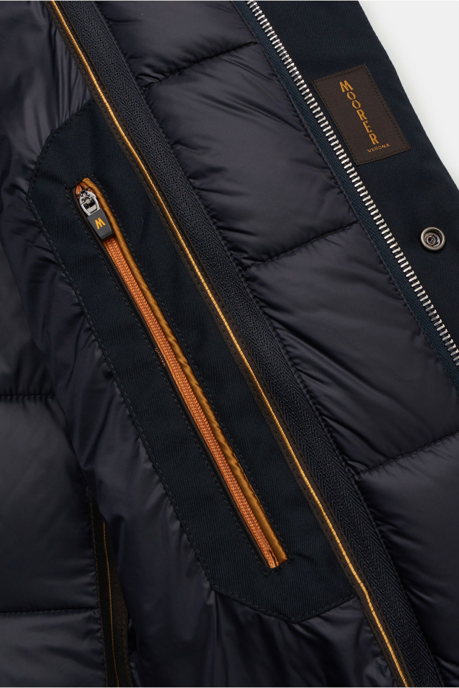 Nahaufnahme aus schräger Perspektive der Innenansicht der Moorer Daunenjacke 'Imel' dark navy mit funktionaler Microfaser, weichem Griff, wasserabweisend, wärmender Gänsedaunenfüllung, Slim Fit, Stehkragen mit verstaubarer Kapuze, herausnehmbarer Double-F