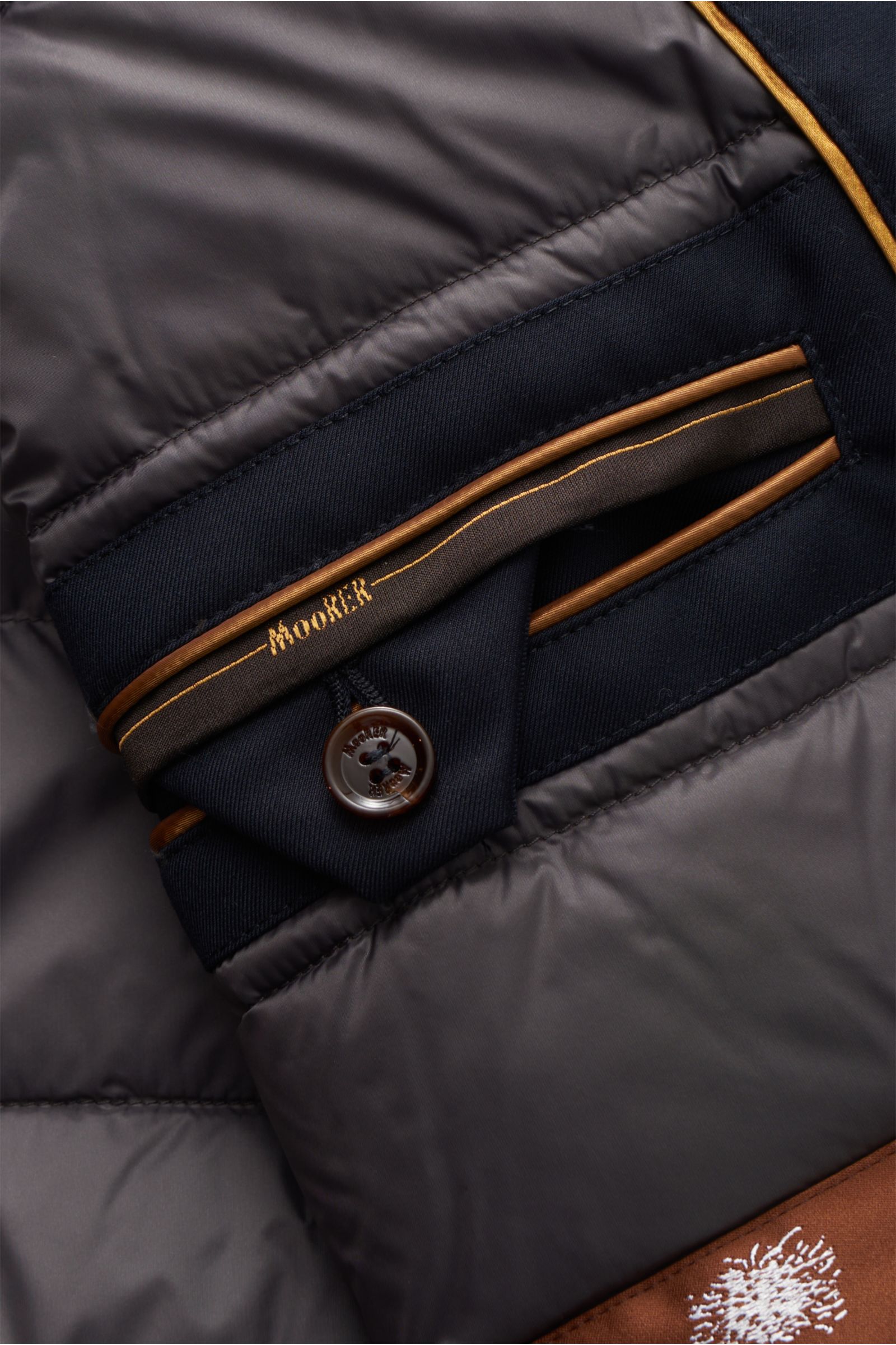 Close-up view of the inside pocket and button detail of the Moorer Down jacket 'Albini' navy, showing quilted lining and stitched branding.

The short cut, luxurious water repellent jacket 'Albini' with detachable hood by MOORER has a warm yet lightwei