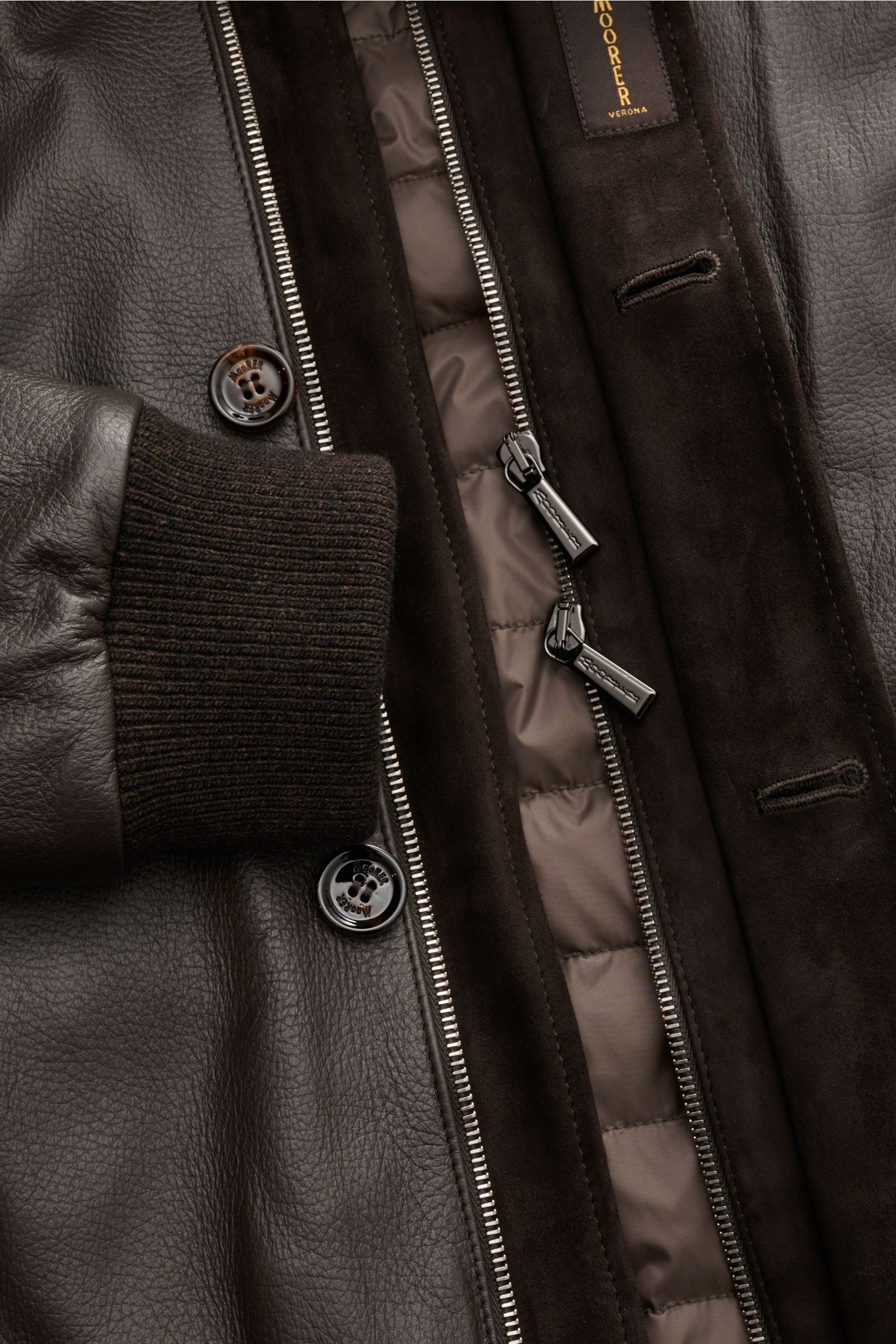 Close-up view of the Moorer Down leather blouson 'Cleros' dark brown, showing smooth deerskin, ribbed sleeve cuff, two-way zip, and quilted lightweight down lining.