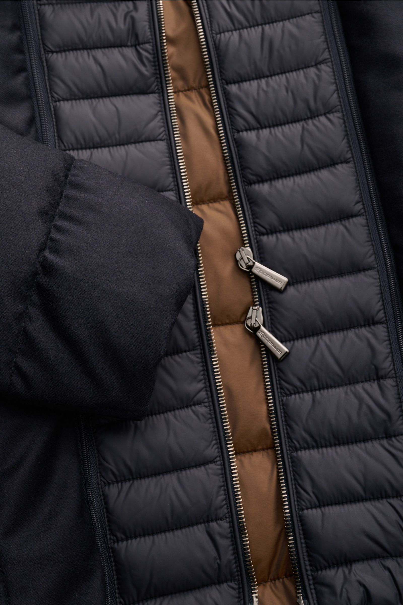 Close-up front view of the Moorer Daunenjacke 'Calegari' navy showing the quilted water-repellent outer fabric, dual zipper, and sleeve details. Stilvoll jeder Wetterlage trotzen wir mit der langen Jacke 'Calegari' aus dem Hause MOORER – das speziell bear