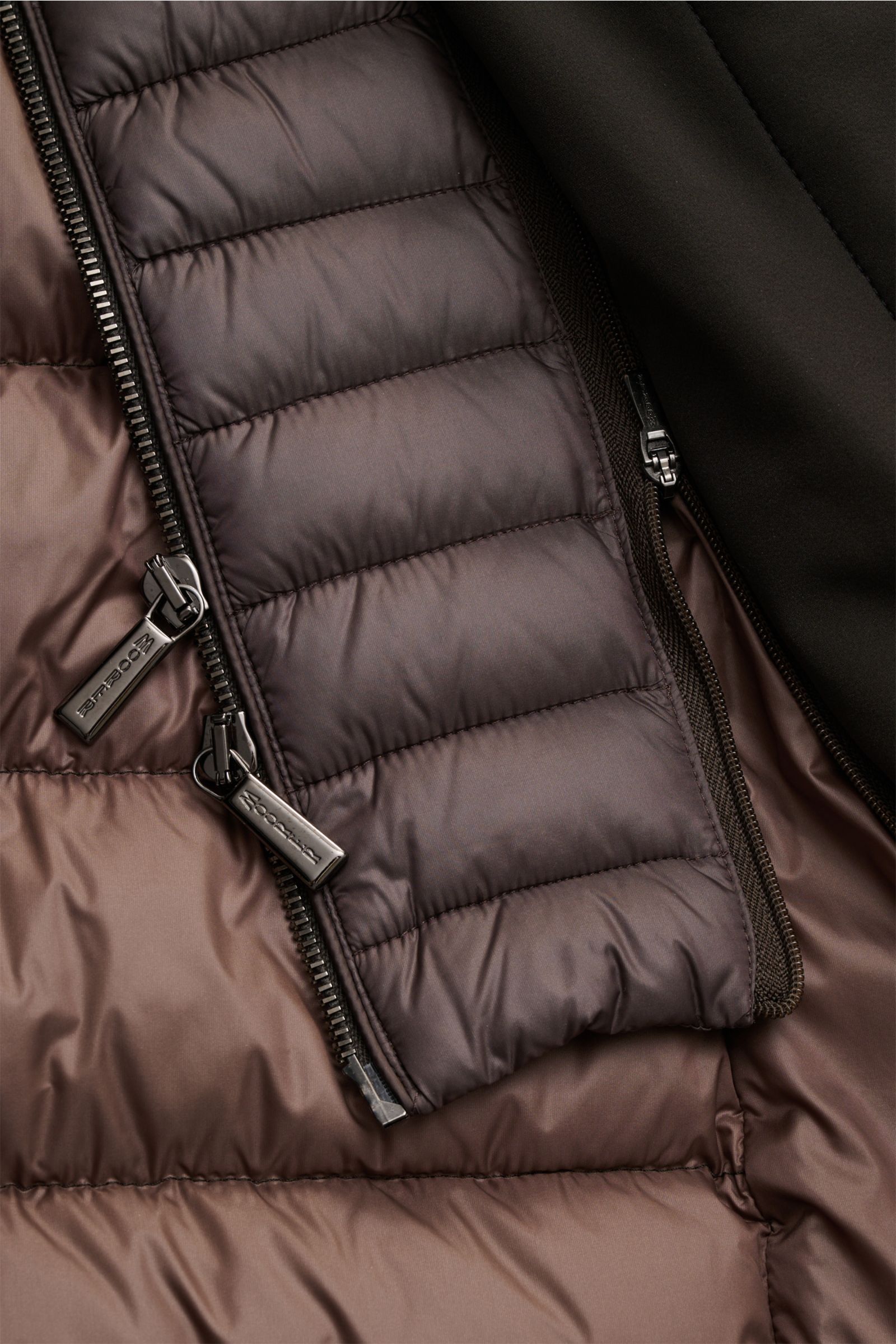 Nahaufnahme der Innenseite der Moorer Daunenjacke 'Calegari' graubraun, Detailansicht der wasserabweisenden Microfaser, glatten Oberfläche, herausnehmbaren Double-Front mit zwei Reißverschlüssen und geschmeidigem Futterstoff.