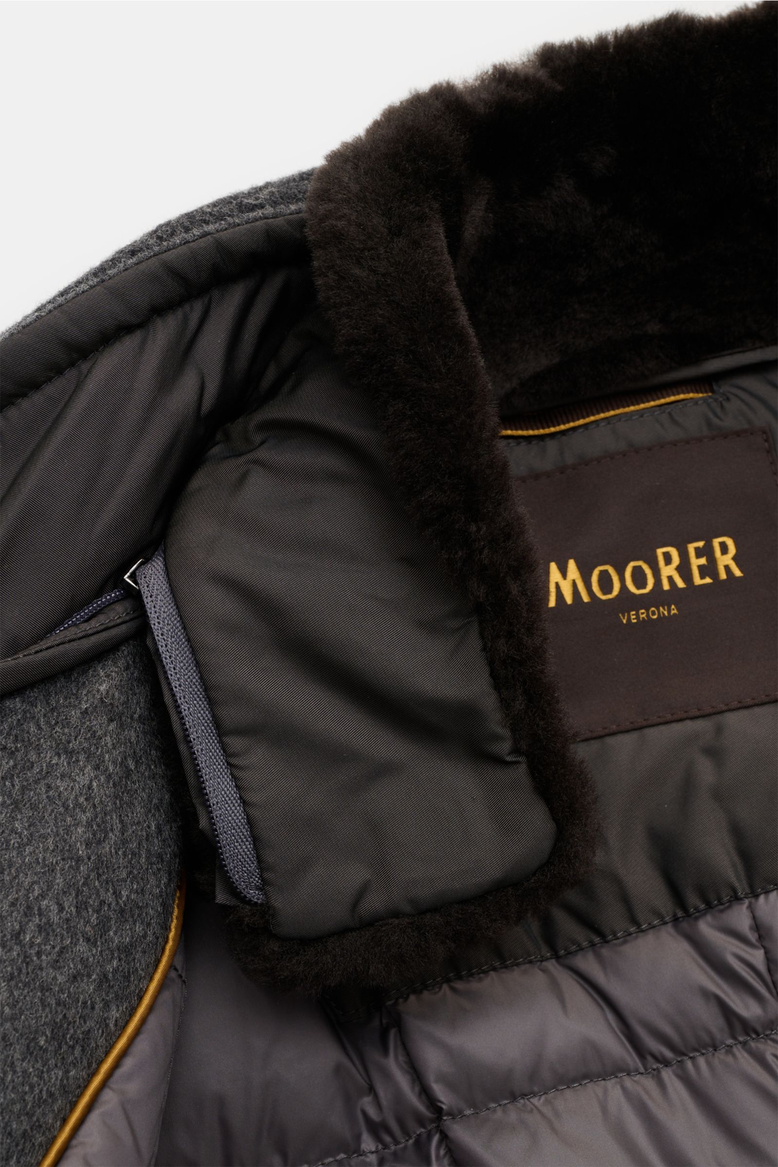 Close-up interior view of the Moorer Down jacket 'Bond' grey mottled showing black quilted lining, soft fur collar, and brand label. 

Italian tailoring meets functionality: This down jacket by MOORER keeps you comfortably warm even at temperatures down t