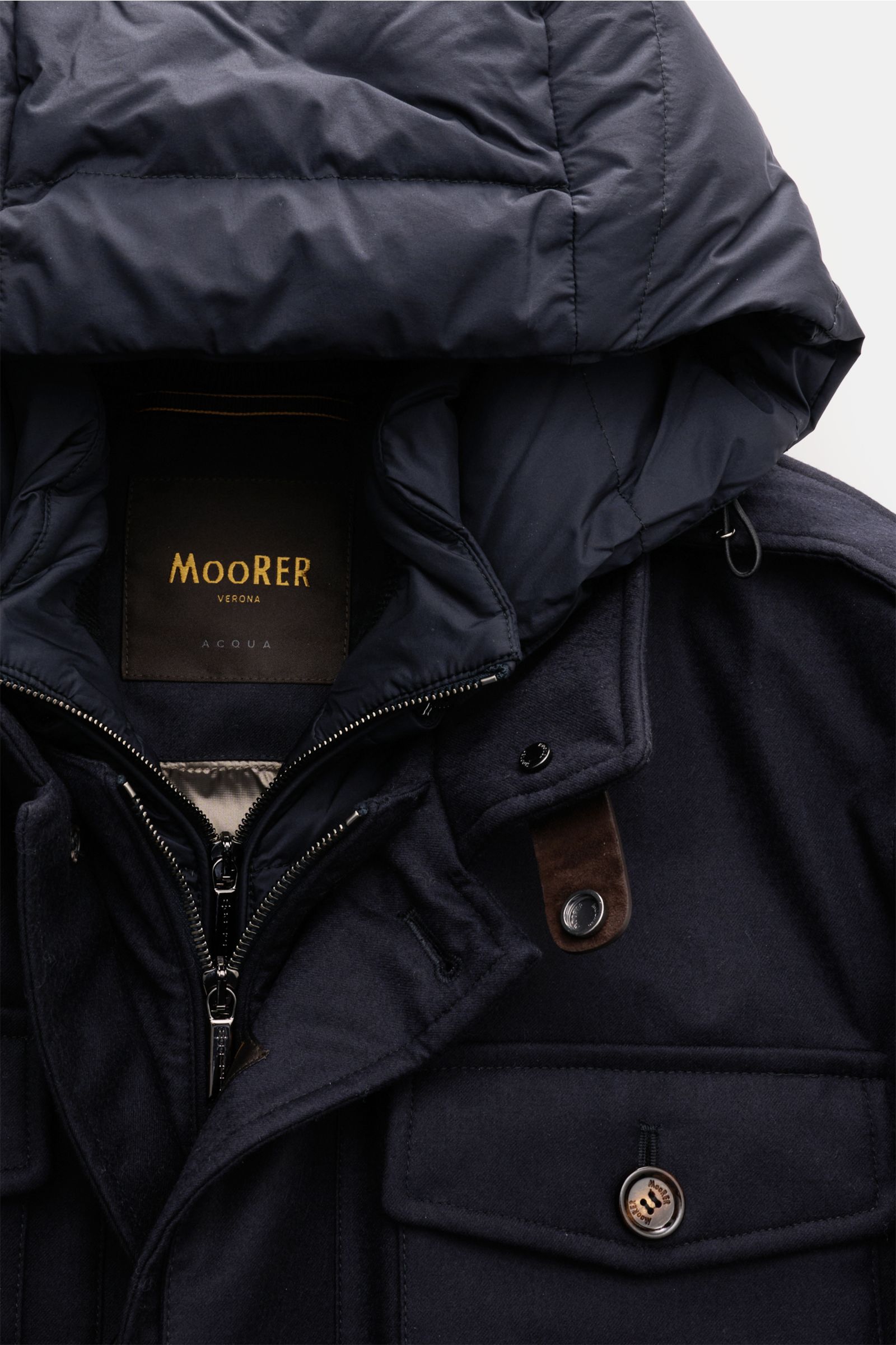 Close-up front view of the Moorer Daunenjacke 'Isac' navy showing the zipper, buttoned flap pocket, collar, and hood details. Stilvoll durch kalte Tage: Die Jacke 'Isac' von MOORER überzeugt mit einem edlen, wasserabweisenden Schurwoll-Mix und einer wä