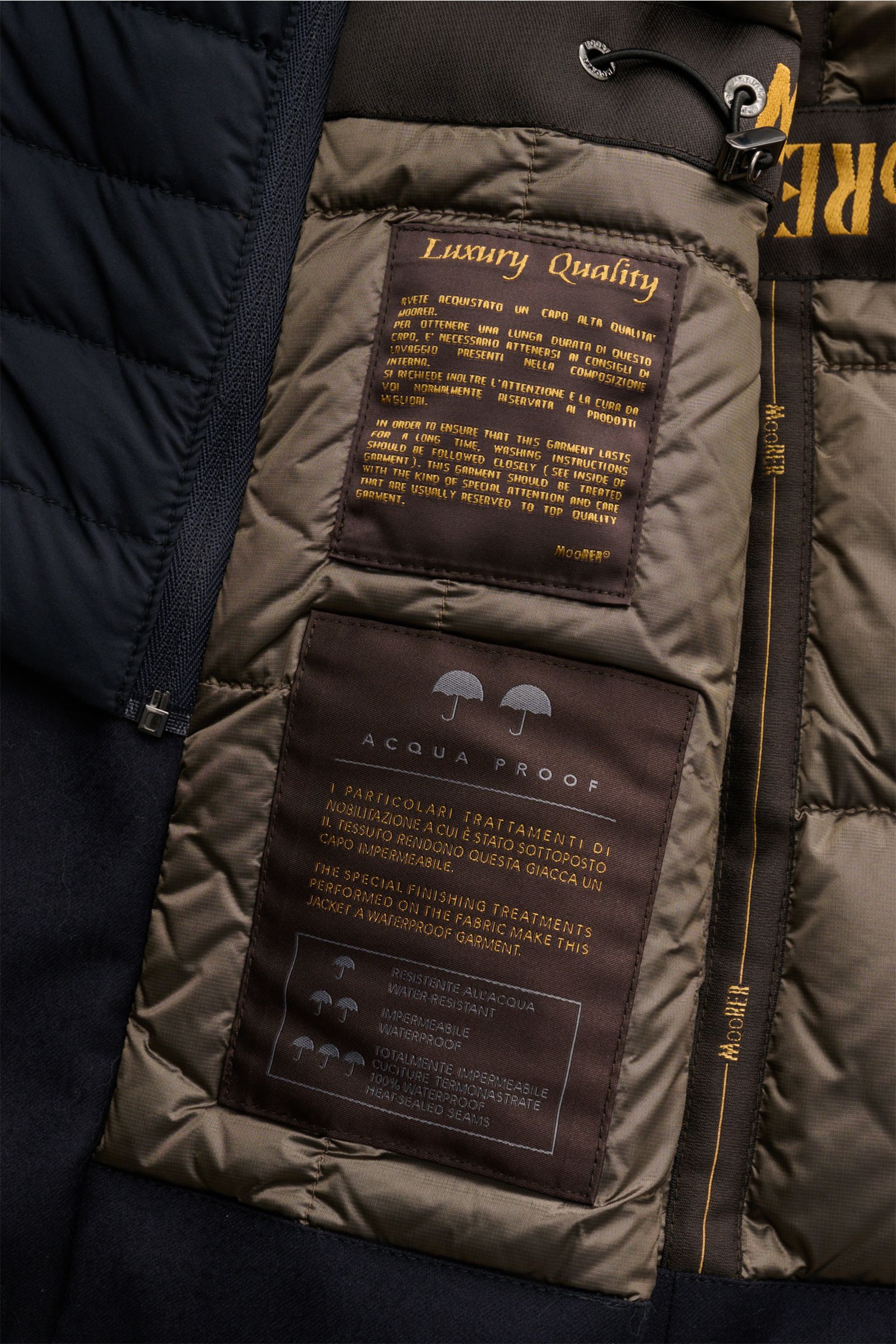 Close-up interior view of Moorer Daunenjacke 'Isac' navy showing luxury quality and waterproof fabric labels, brown and navy quilted lining.

Stilvoll durch kalte Tage: Die Jacke 'Isac' von MOORER überzeugt mit einem edlen, wasserabweisenden Schurwoll-