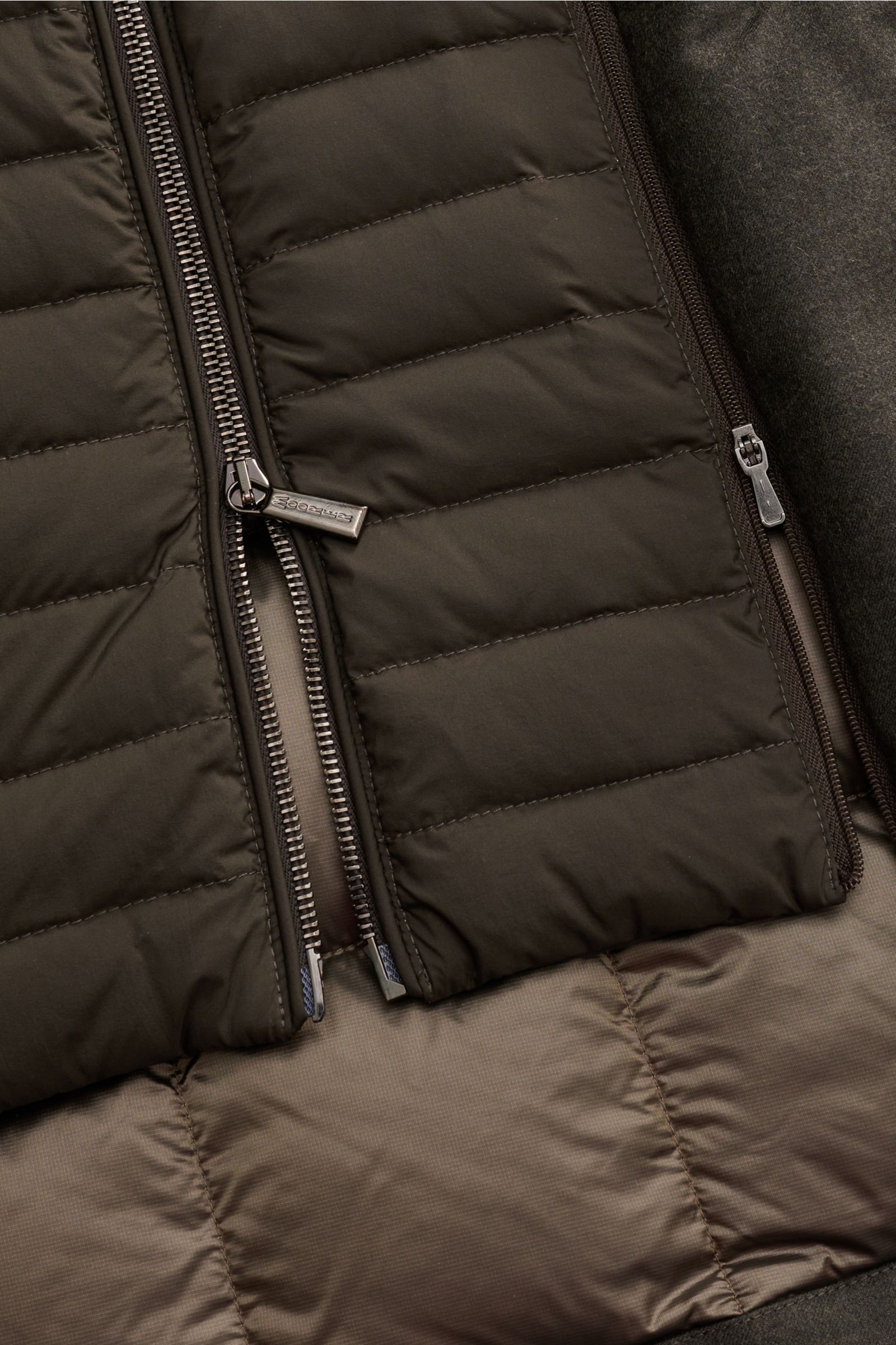 Close-up front view of the Moorer Daunenjacke 'Isac' oliv meliert, showing the quilted, water-repellent Schurwoll-Mix fabric, double zipper, and soft textures. Stilvoll durch kalte Tage: Die Jacke 'Isac' von MOORER überzeugt mit einem edlen, wasserabwe