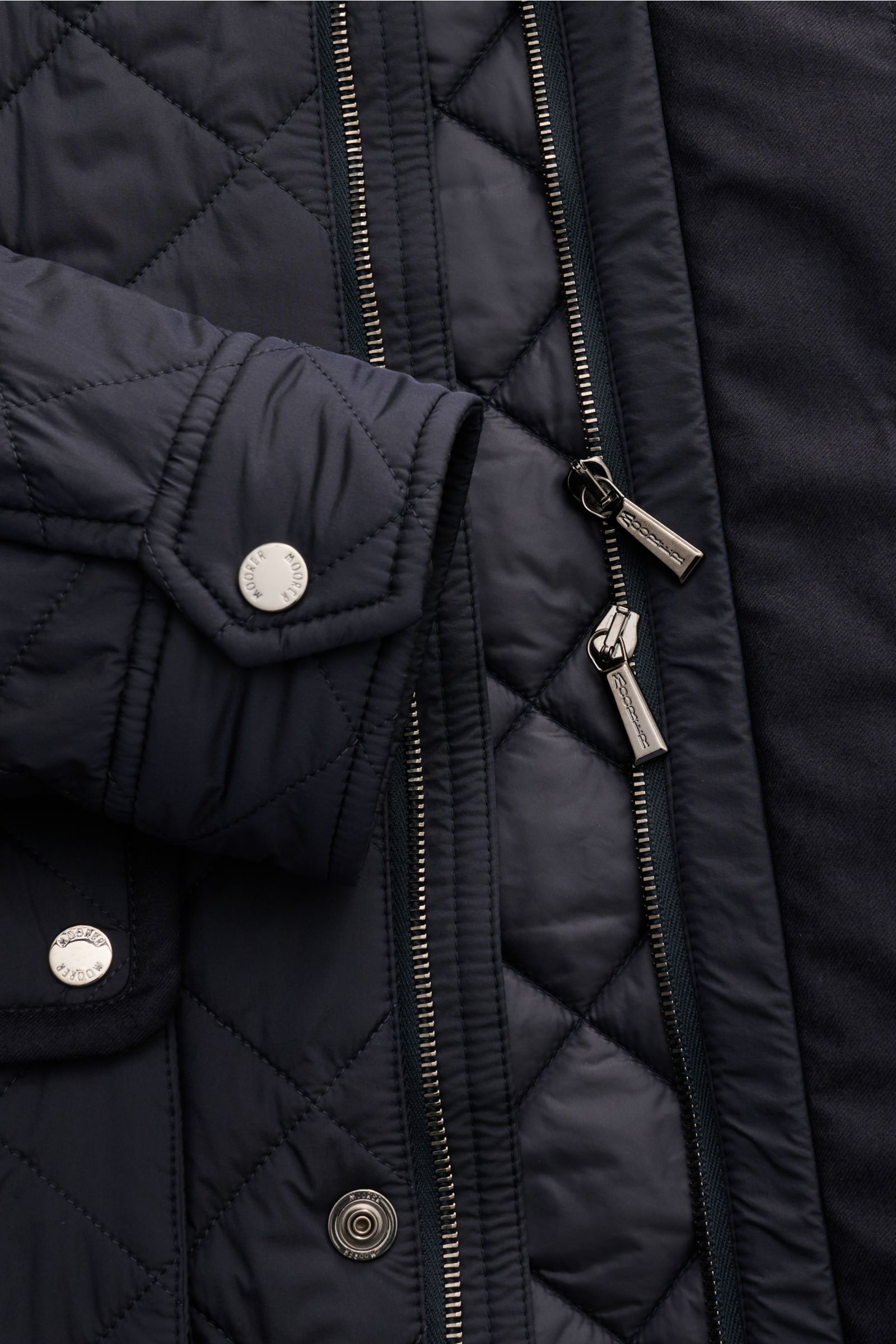 Close-up front view of Moorer Daunenjacke 'Zavyer' dark navy quilted jacket showing diamond stitching, zippers, and snap buttons.

Stilvoll durch die kühle Jahreszeit wird Sie die edle Steppjacke 'Zavyer' von MOORER begleiten, die dank leichter Daunenf