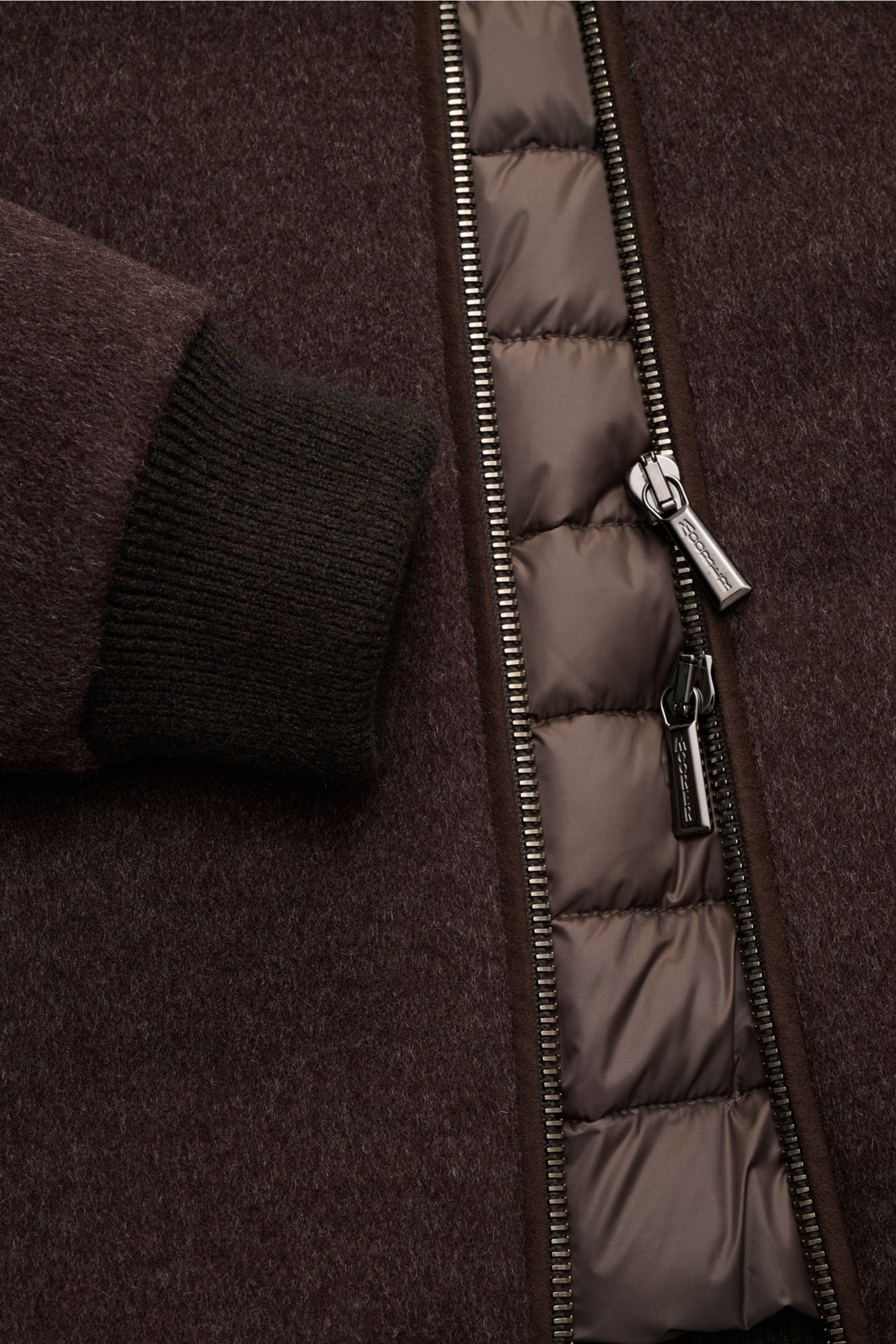 Nahaufnahme des dunkelbraunen Moorer Daunenblouson 'Bellati' mit gestrickter Außenseite, Zwei-Wege-Reißverschluss und elastischem Ärmelabschluss.