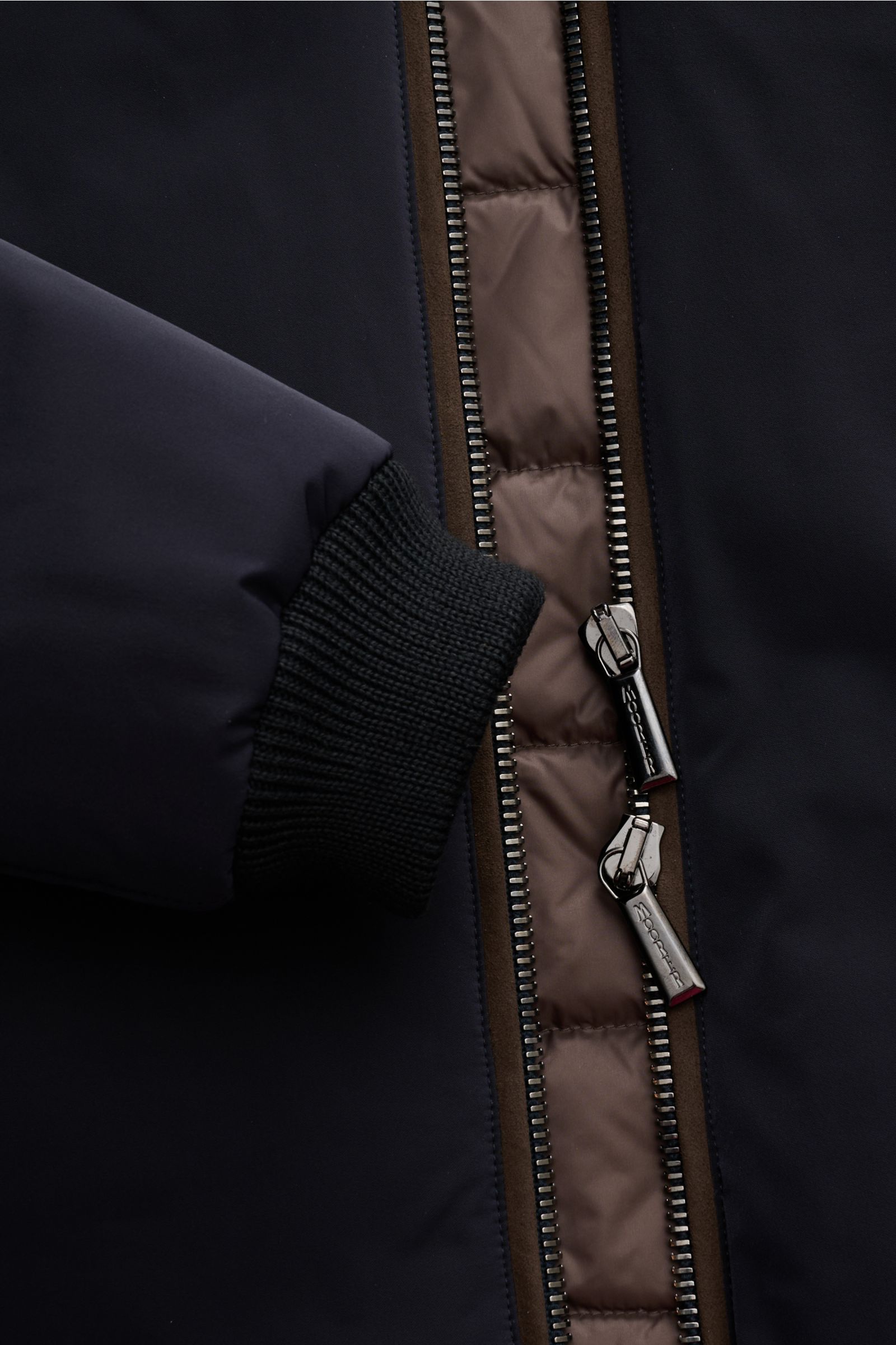 Nahaufnahme des robusten Zwei-Wege-Reißverschlusses und des elastischen Ärmelbündchens des Moorer Daunenblouson 'Celotti' dark navy.