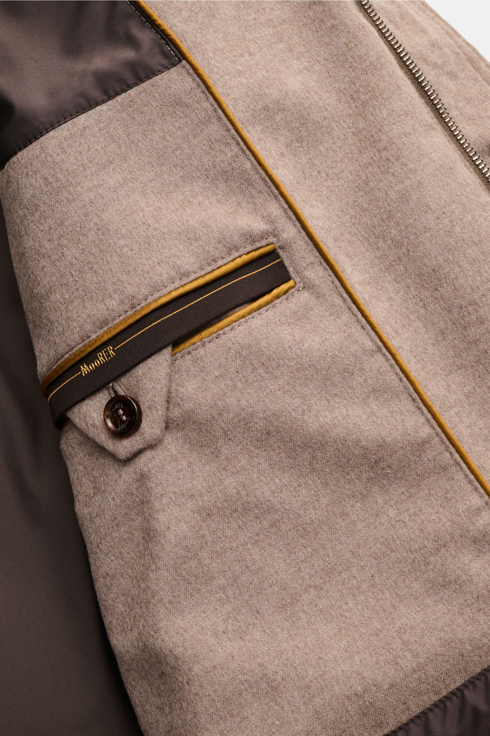 Detailaufnahme des Innenfutters vom Moorer Cashmere Daunenparka 'Gorner' taupe mit weichem Cashmere, Knopfverschluss und edler Naht.