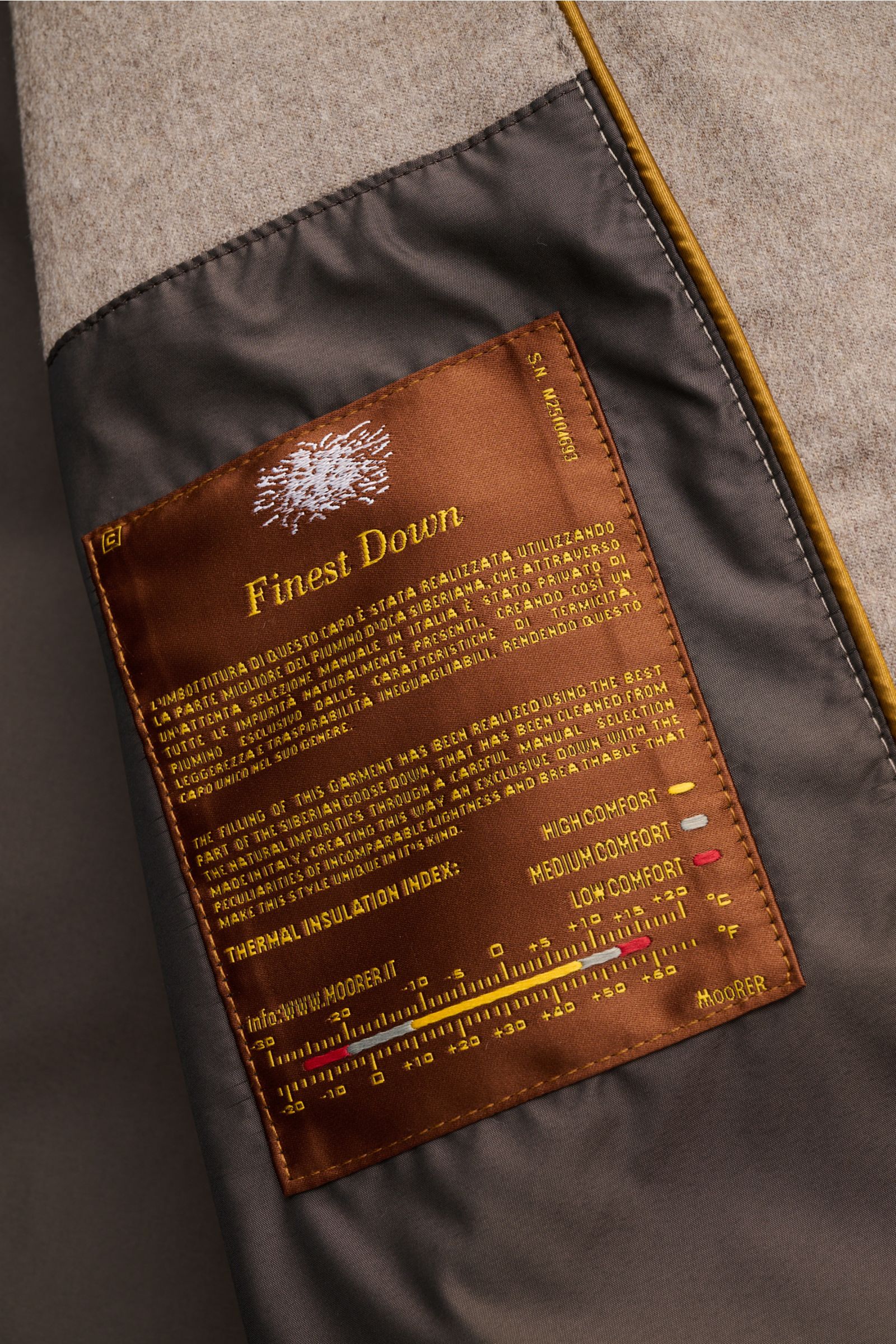 Nahaufnahme des Innenfutters und Etiketts des Moorer Cashmere Daunenparka 'Gorner' taupe mit wärmender Daunenfüllung aus feinem Cashmere.