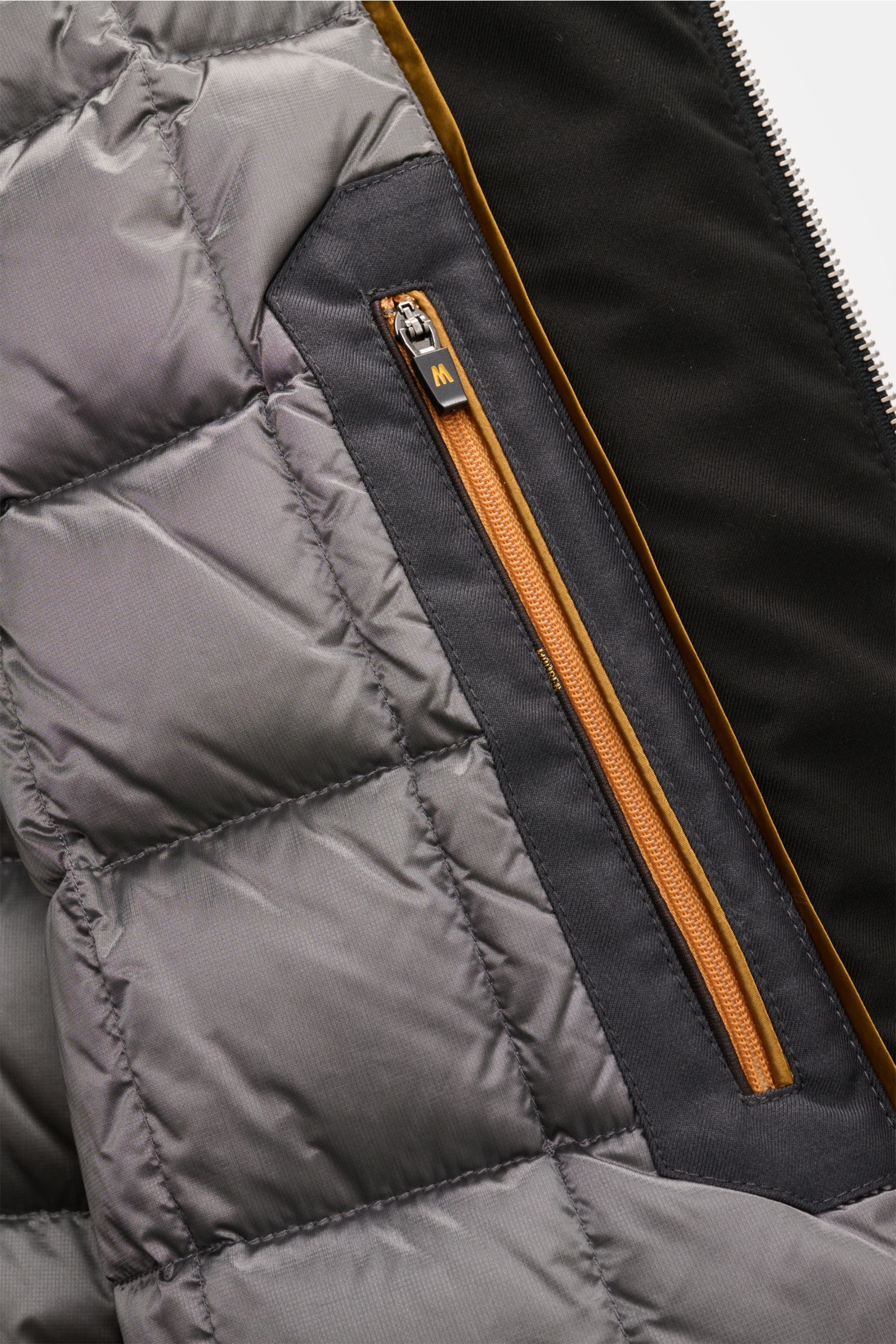 Close-up interior view of the Moorer Daunenjacke 'Drive Pum' schwarz showing quilted gray lining and zippered pocket with orange trim.