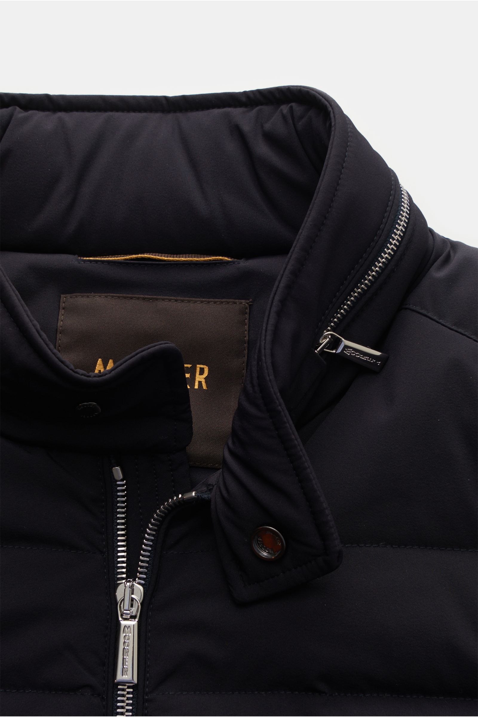 Nahaufnahme der wasserabweisenden Moorer Daunenjacke 'Filippo' dark navy, Slim Fit mit Stehkragen, versteckter Kapuze, Gänsedaunenfüllung, Zwei-Wege-Reißverschluss und funktionalem, glattem Microfaserstoff.