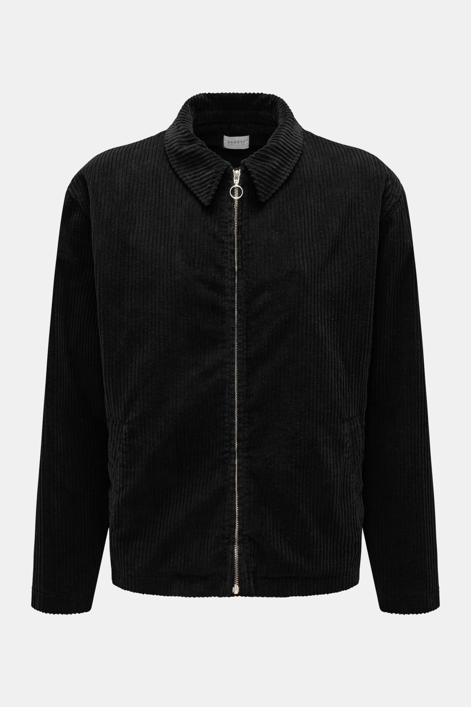 04651/ A trip in a bag Cordjacke schwarz, frontal fotografiert, aus elastischer Baumwolle mit Metall-Reißverschluss, Umlegekragen und paspelierten Taschen.