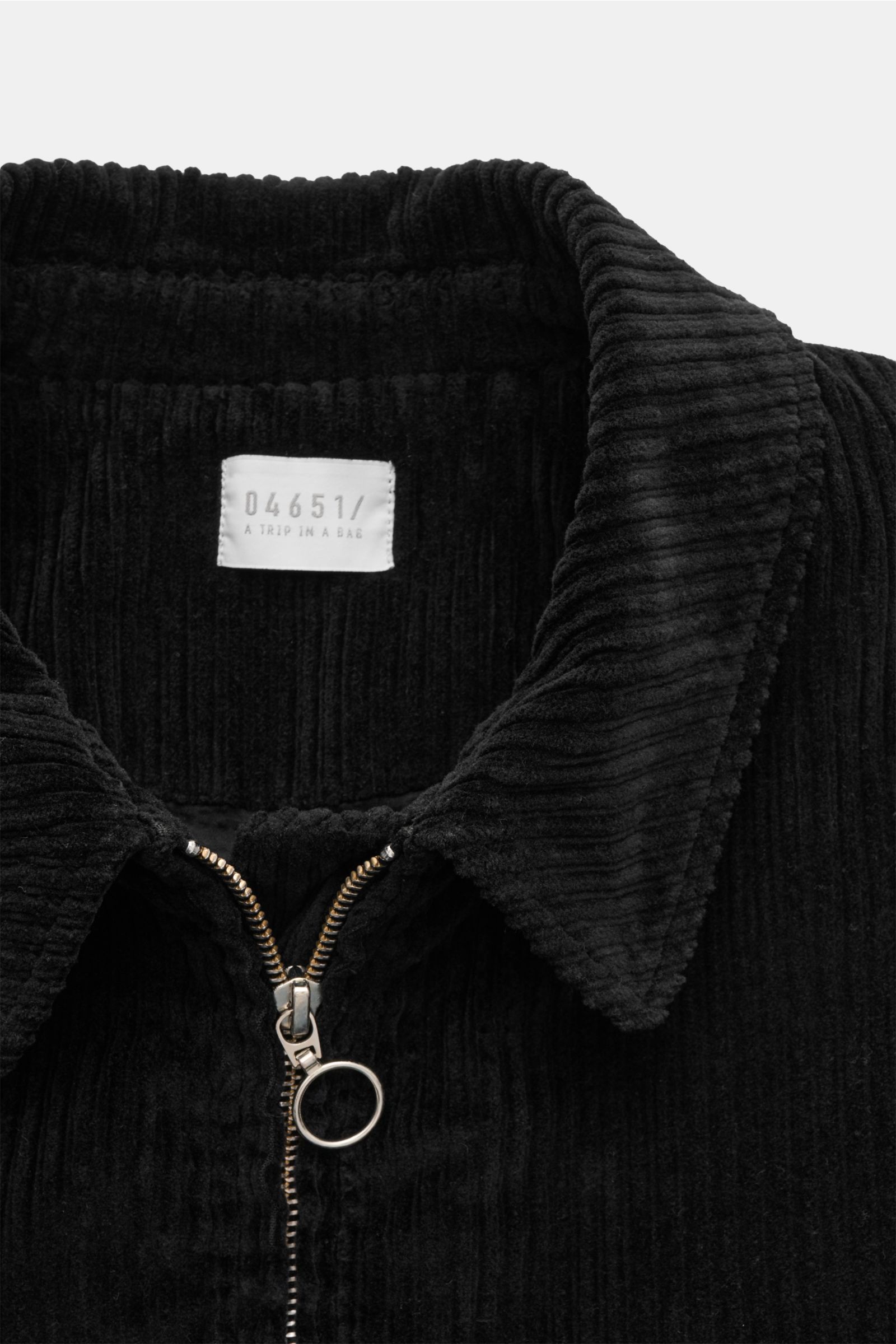 Schwarze 04651/ A trip in a bag Cordjacke in Nahaufnahme von oben, mit Umlegekragen, Metall-Reißverschluss und weichem Cordstoff.