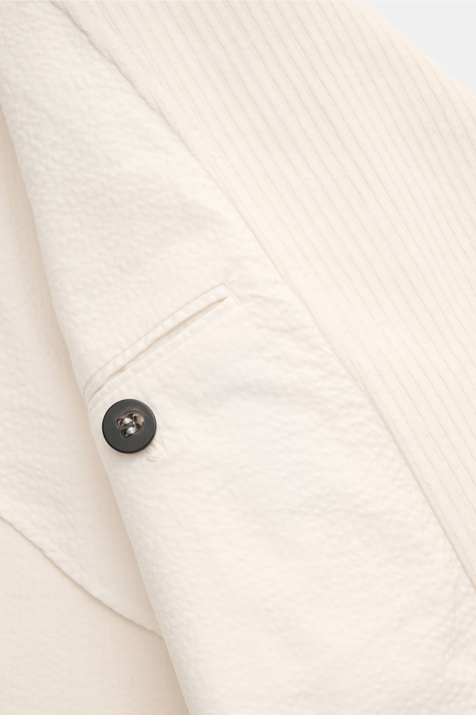 Nahaufnahme der cremefarbenen 04651/ A trip in a bag Cord-Cabanjacke mit voluminösem Breitcord, Knopfdetail und Seersucker-Futterstoff.