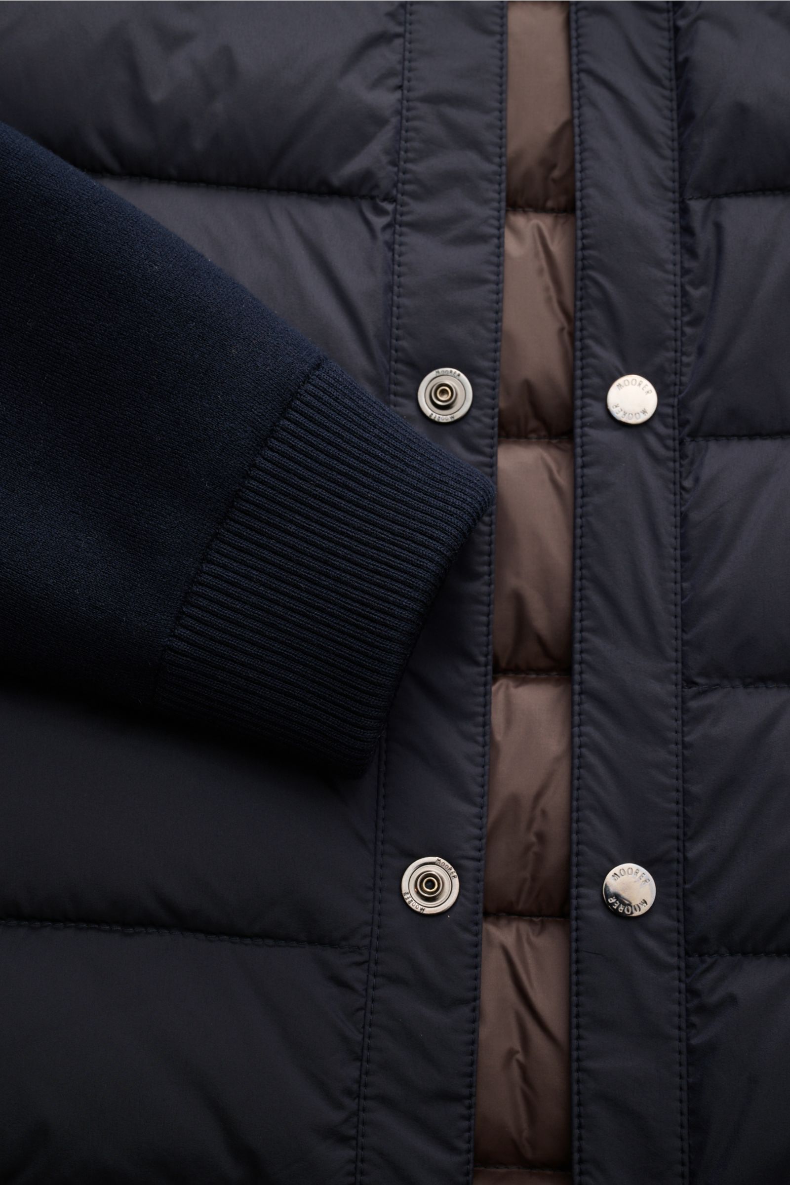 Close-up front view of Moorer Daunenjacke 'Ardesi' navy showing elastic microfiber sleeve cuff, smooth grip fabric, six-button placket, and brown quilted lining.