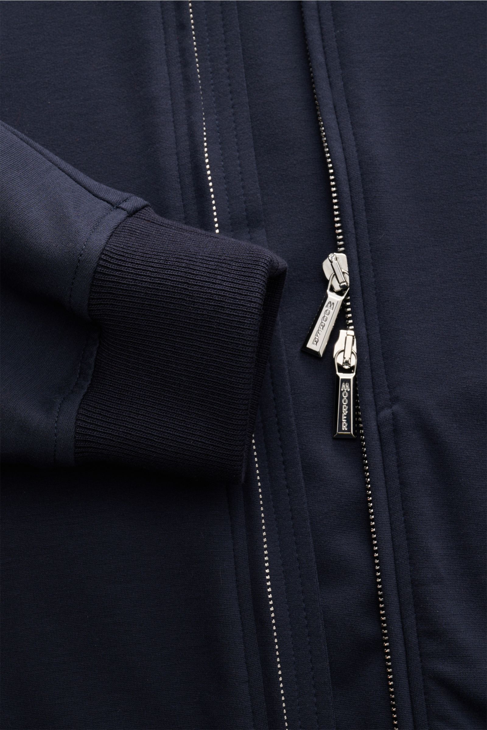 Close-up detail shot from the front of the Moorer Blouson 'Astaire' navy, showing the two-way zipper with branded pulls and ribbed cuff. Sportive Styles im Herbst: Der Jersey-Blouson von MOORER präsentiert sich als ideales Layering-Piece für legere Outfit
