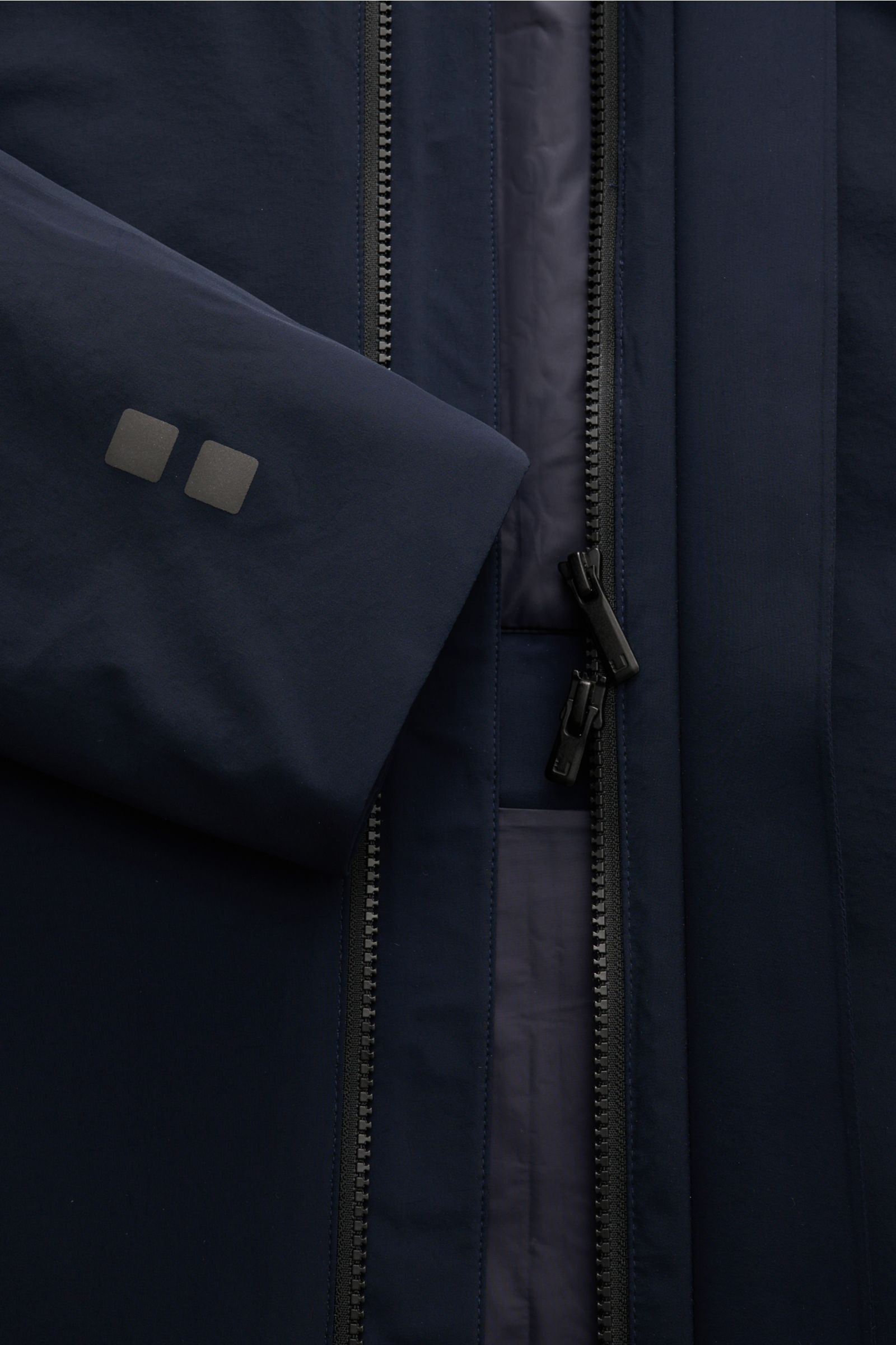 Close-up front view of the navy UBR Parka 'Regulator' showing the dual zipper, sleeve with logo, and smooth fabric.

High-Tech-Materialien und innovative Fertigungstechniken sind das Fachgebiet der norwegischen Marke UBR: Der Parka 'Regulat