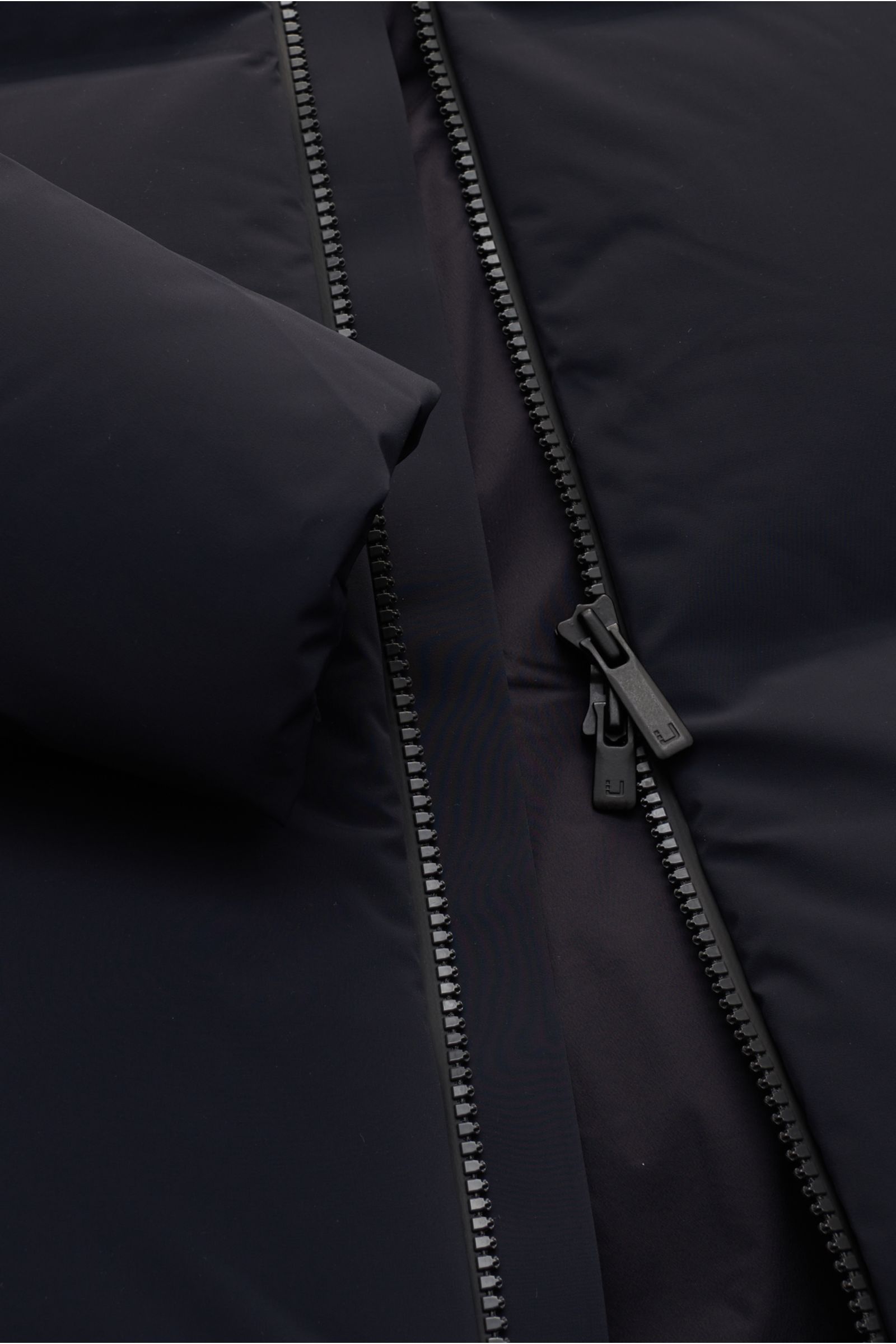 UBR Daunenjacke 'Titan' schwarz, Detailaufnahme von Reißverschluss und Ärmel, wasserdicht, atmungsaktiv, mit Gänsedaunenfüllung.