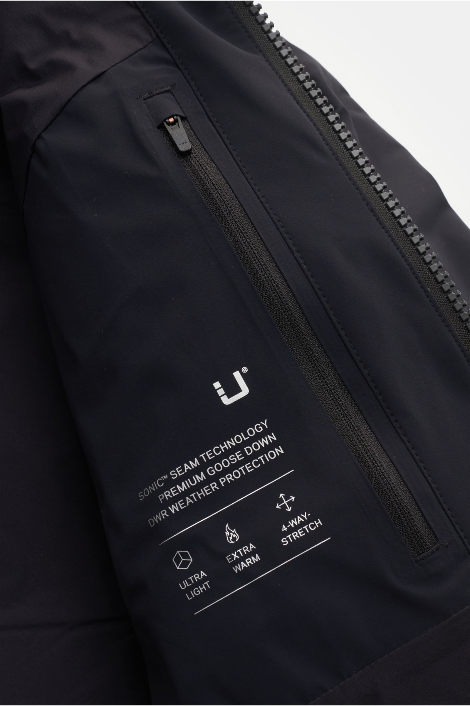 Nahaufnahme der schwarzen UBR Daunenjacke 'Titan' mit Reißverschluss und reflektierendem Logo, technische Microfaser, wasserdicht, atmungsaktiv, Gänsedaunenfüllung, Regular Fit.