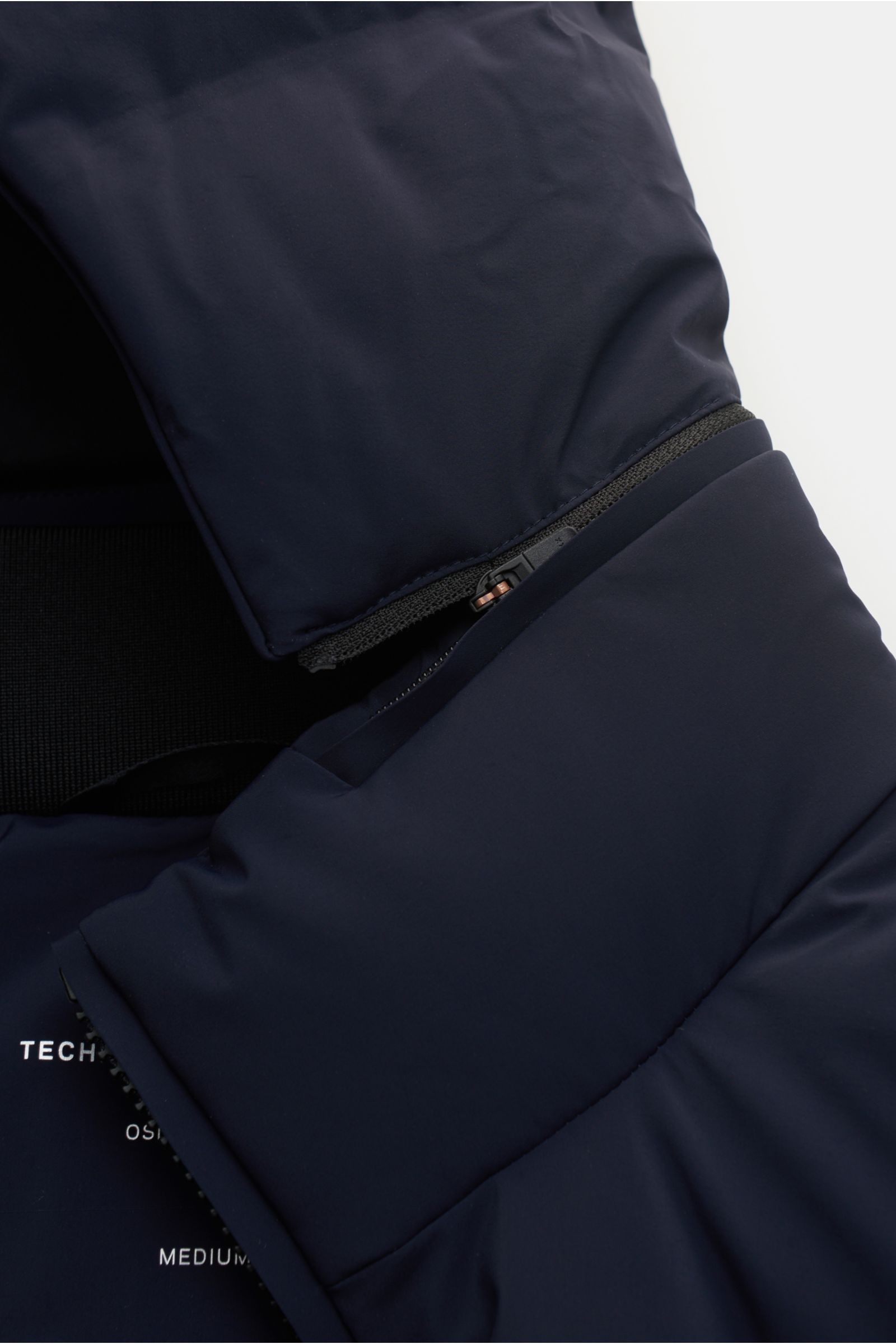 Nahaufnahme der UBR Daunenjacke 'Bolt' navy von oben, zeigt abnehmbare Kapuze, wasserfeste Membran, versiegelte Nähte, Slim Fit und Zipper-Tasche.