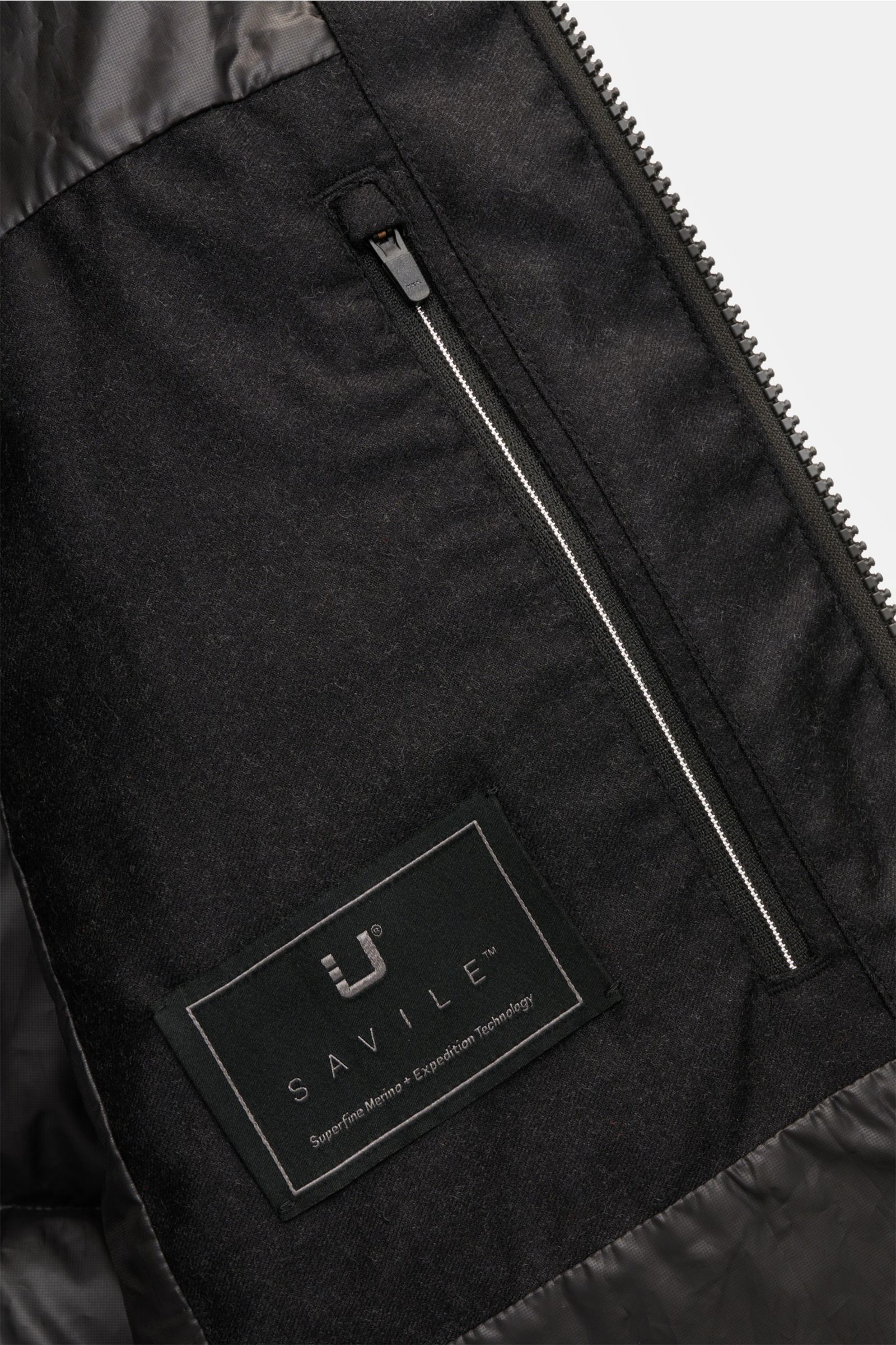Nahaufnahme der Innenseite der UBR Daunenjacke 'Concord' schwarz mit Reißverschluss-Innentasche und Savile Merino Woll-Label, reine Wolle, weicher Griff, wärmende Daunenfüllung, Slim Fit, Zwei-Wege-Reißverschluss, wattierte, abnehmbare Kapuze, Zipper-Fron