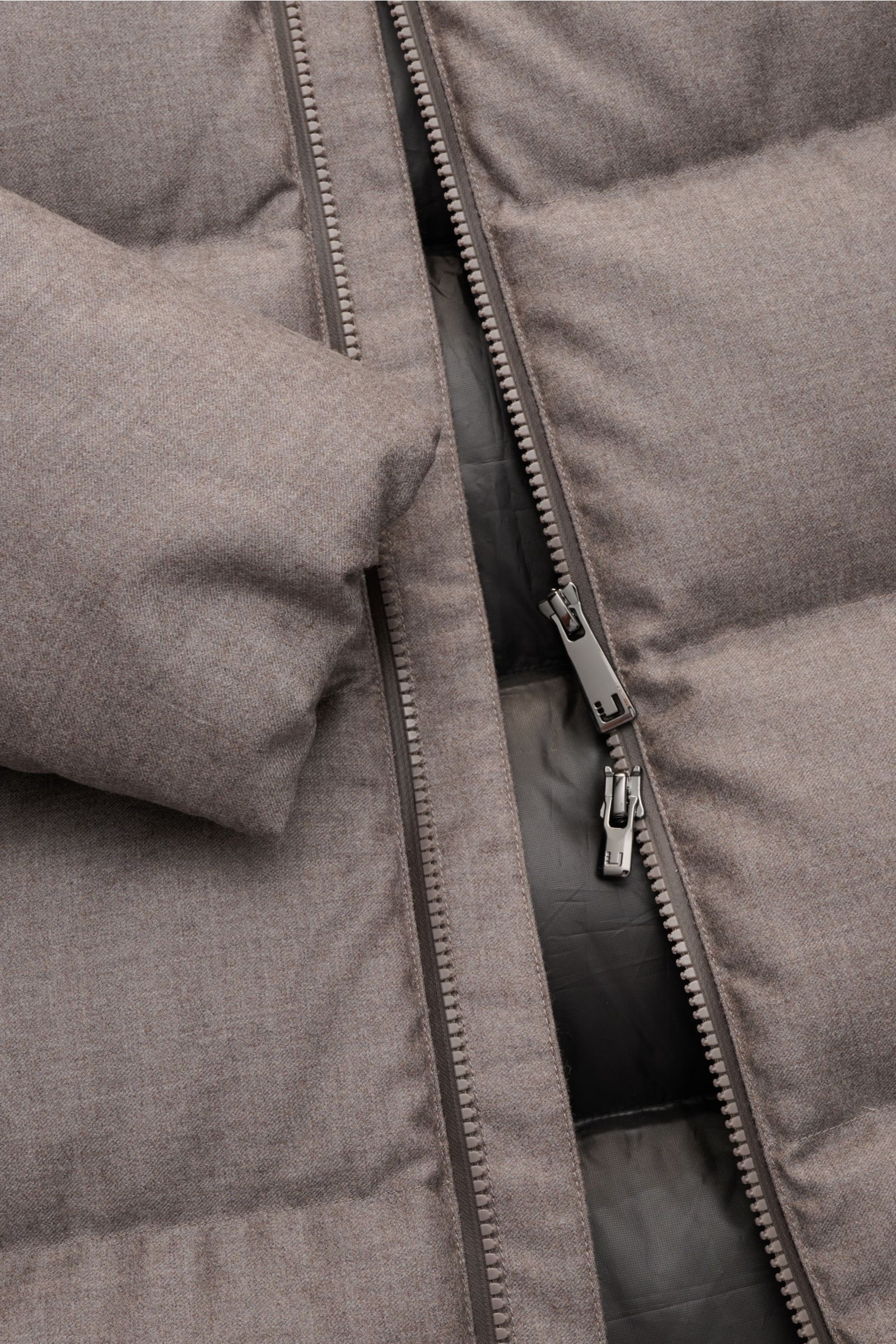 Close-up, top-down view of the grey melange UBR Daunenjacke 'Concord' showing the soft wool fabric, two-way zipper, and padded down filling. Urban style meets high-performance with features like a slim fit, detachable padded hood, zipper front pockets, el