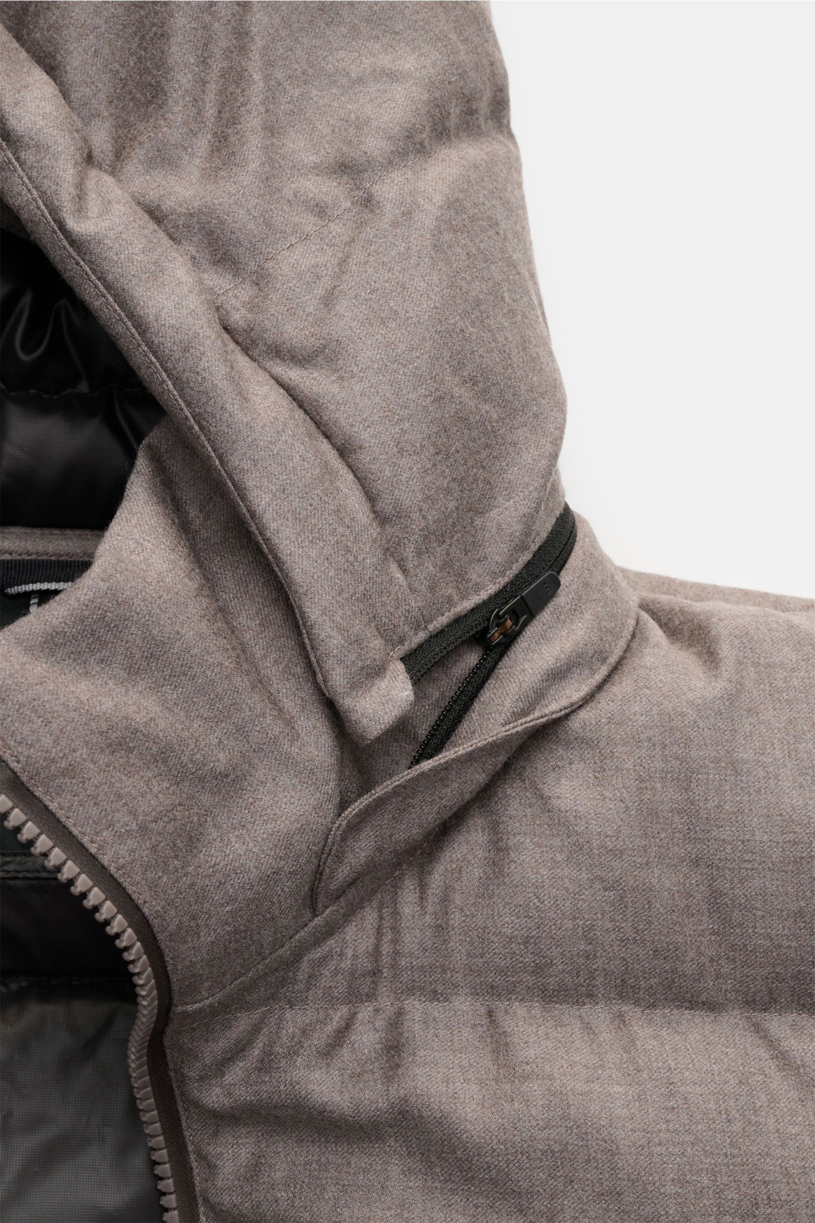 Close-up view of the hood and shoulder area of the UBR Daunenjacke 'Concord' grau meliert, a slim-fit, gray melange down jacket made from pure wool with a soft touch, featuring a two-way zipper, detachable padded hood, zipper front pockets, elastic cuffs,