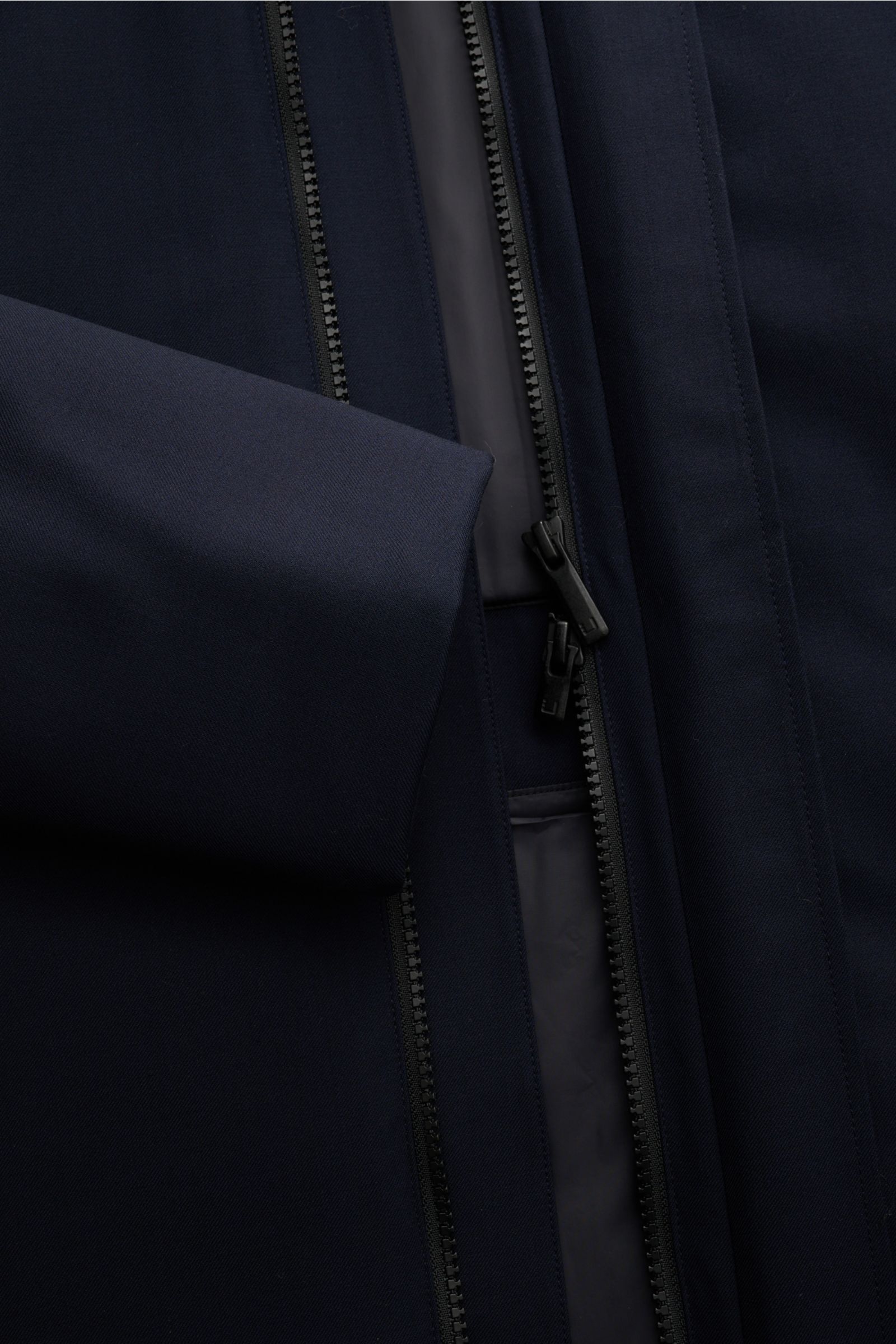 Close-up front view of the navy UBR Parka 'Regulator Parka Savile', showcasing the twill Merinowool fabric, two-way zipper, and smooth inner lining.