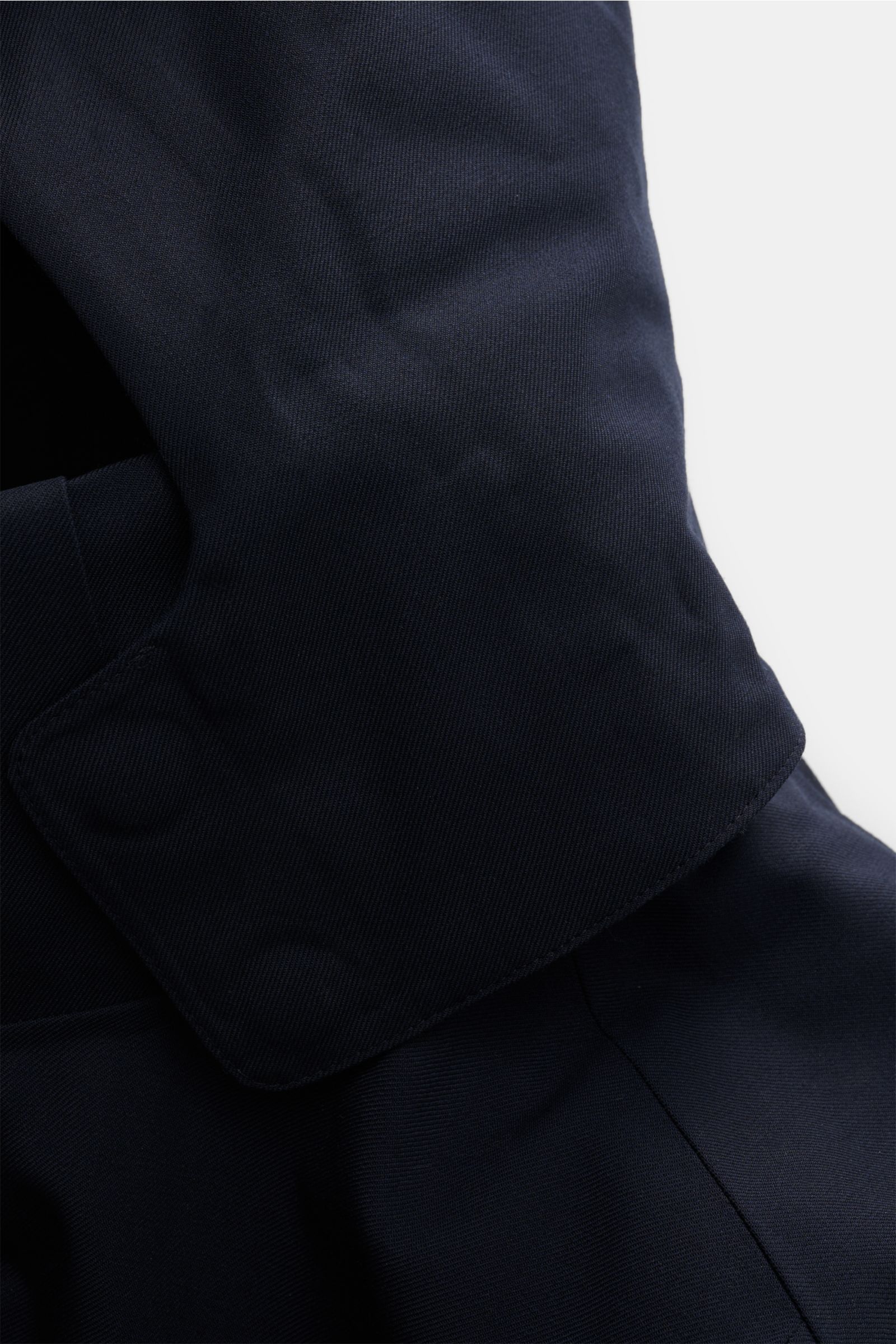 Close-up view of the navy fabric and collar detail of the UBR Parka 'Regulator Parka Savile' navy, showcasing fine merino wool twill with waterproof membrane. This stylish parka features lightweight Primaloft padding, taped seams, slim fit, two-way zipper