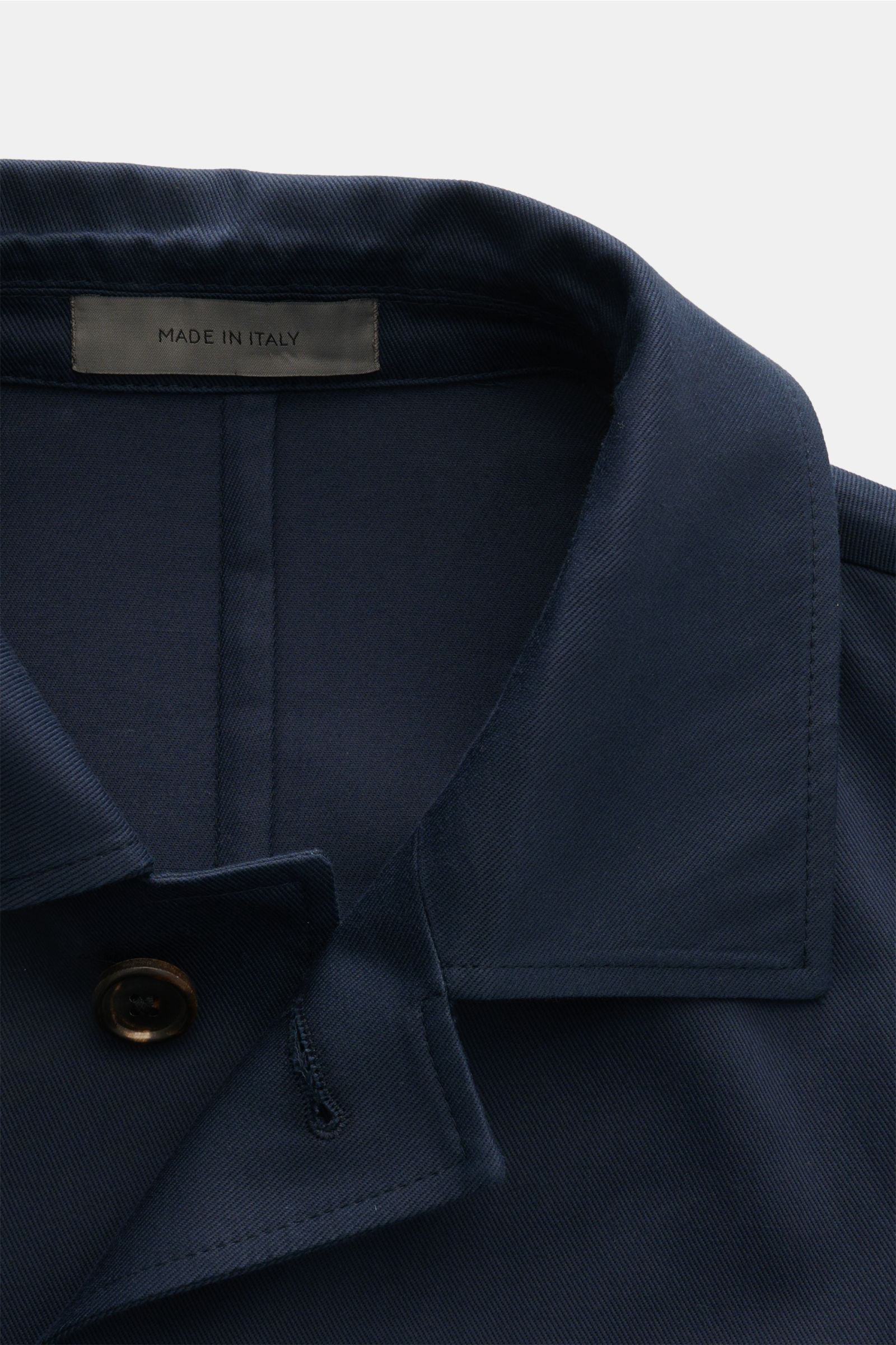 Nahaufnahme der Corneliani Jacke navy aus elastischer Baumwolle mit Umlegekragen, Manschetten und Fünf-Knopf-Leiste, von oben fotografiert.