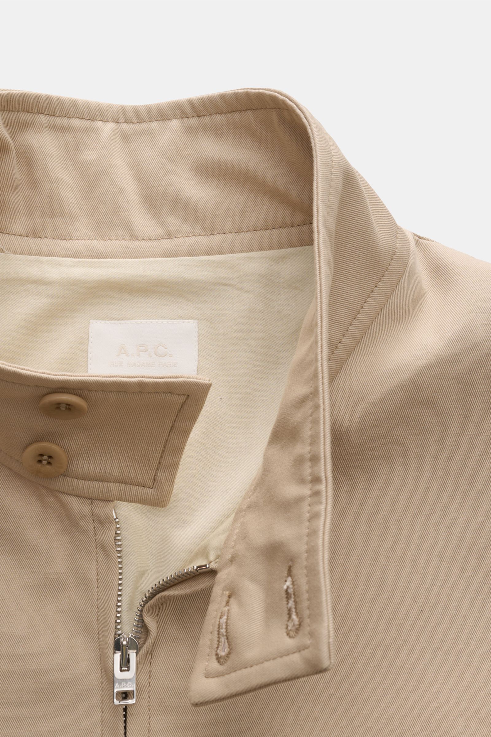 Close-up front view of the A.P.C. Blouson beige collar and zipper, showing high-quality cotton gabardine fabric and tonal stitching. Distinctive, urban and clean: This blouson by A.P.C. plays with clear shapes. High-quality cotton gabardine and tonal logo