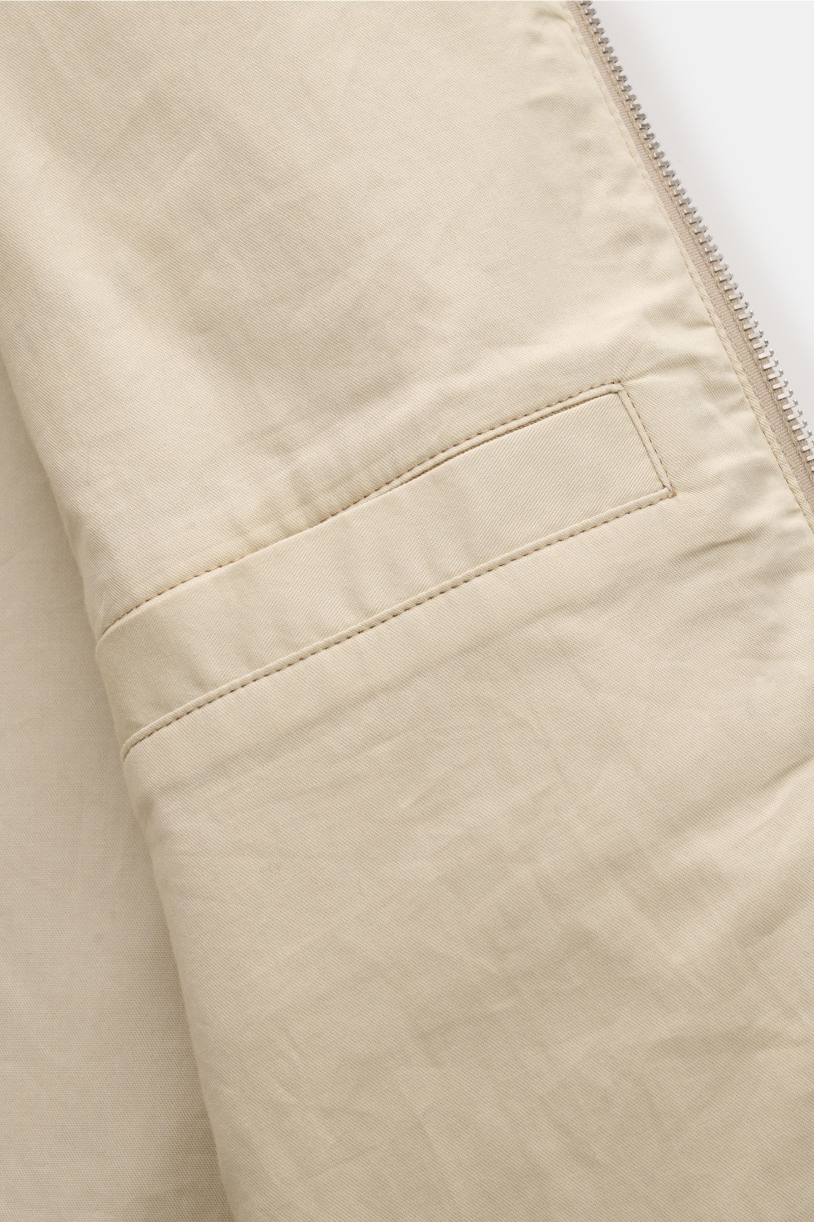 A close-up detail shot from the front side of the A.P.C. Blouson beige, showcasing the tonal stitching and slanted hip pocket. Distinctive, urban and clean: This blouson by A.P.C. plays with clear shapes. High-quality cotton gabardine and tonal logo stitc