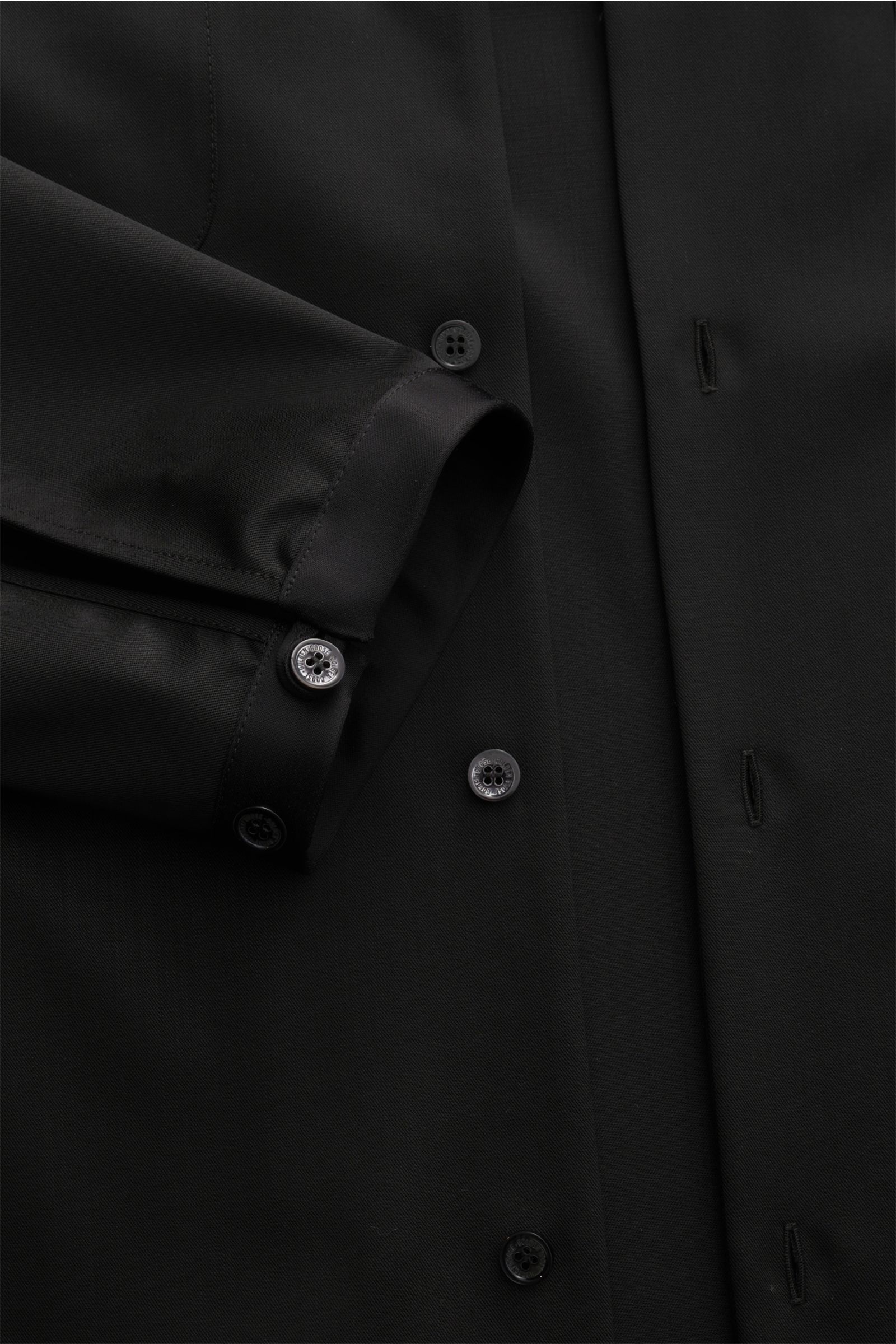 Black close-up image of the Golden Goose Overshirt 'M's Tailored Shirt Paolo W Camp' black, showing the front buttons and sleeve cuff with satin highlights, photographed from a top-down perspective. Uncomplicated, individual, GOLDEN GOOSE: This overshirt 