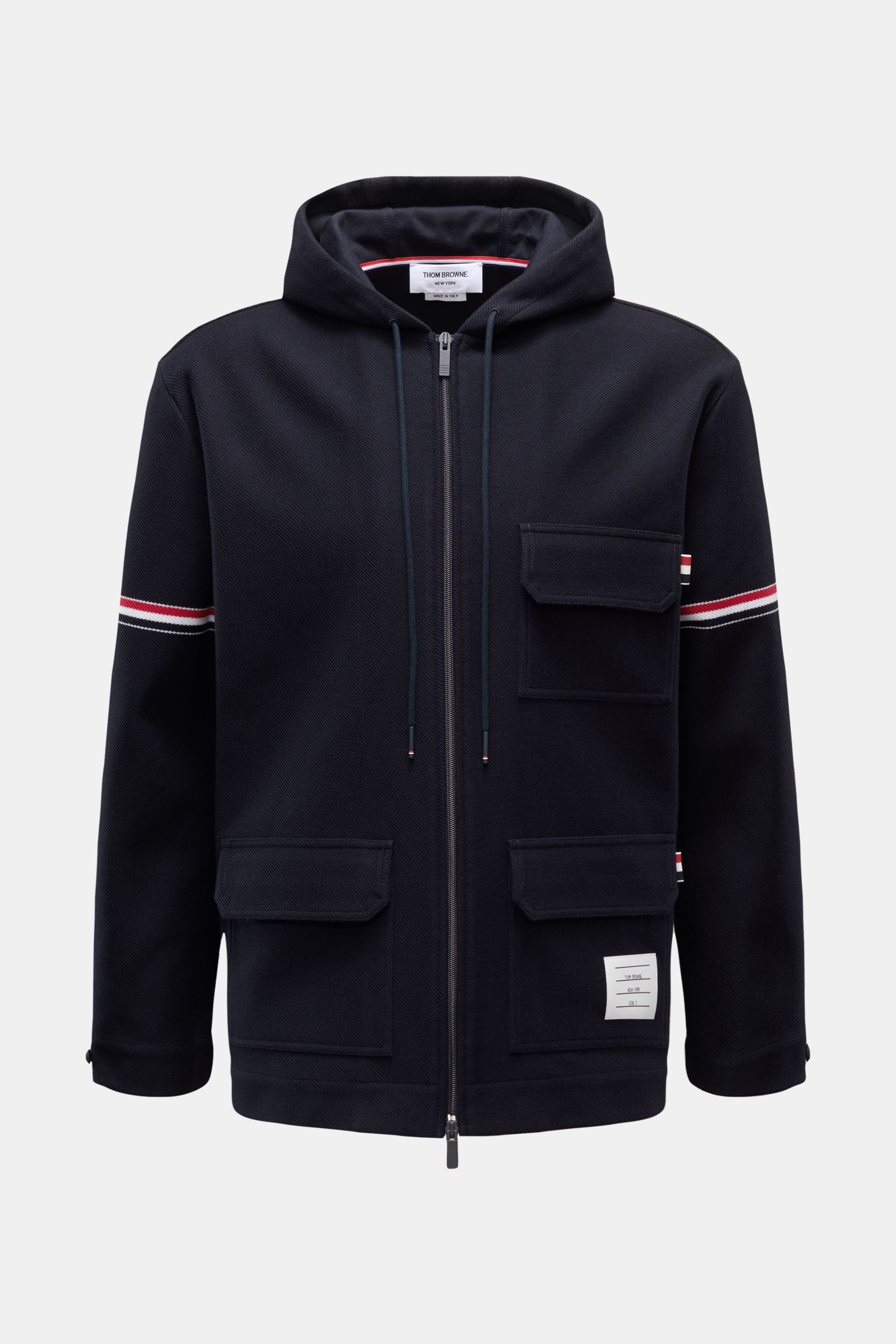 Front view of a Thom Browne Jacke navy, a casual layering piece in breathable pure cotton with a lightly textured structure. Features include a regular fit, two-way zipper, hood with drawstrings, three front pockets with flaps, buttoned sleeve cuffs, sign