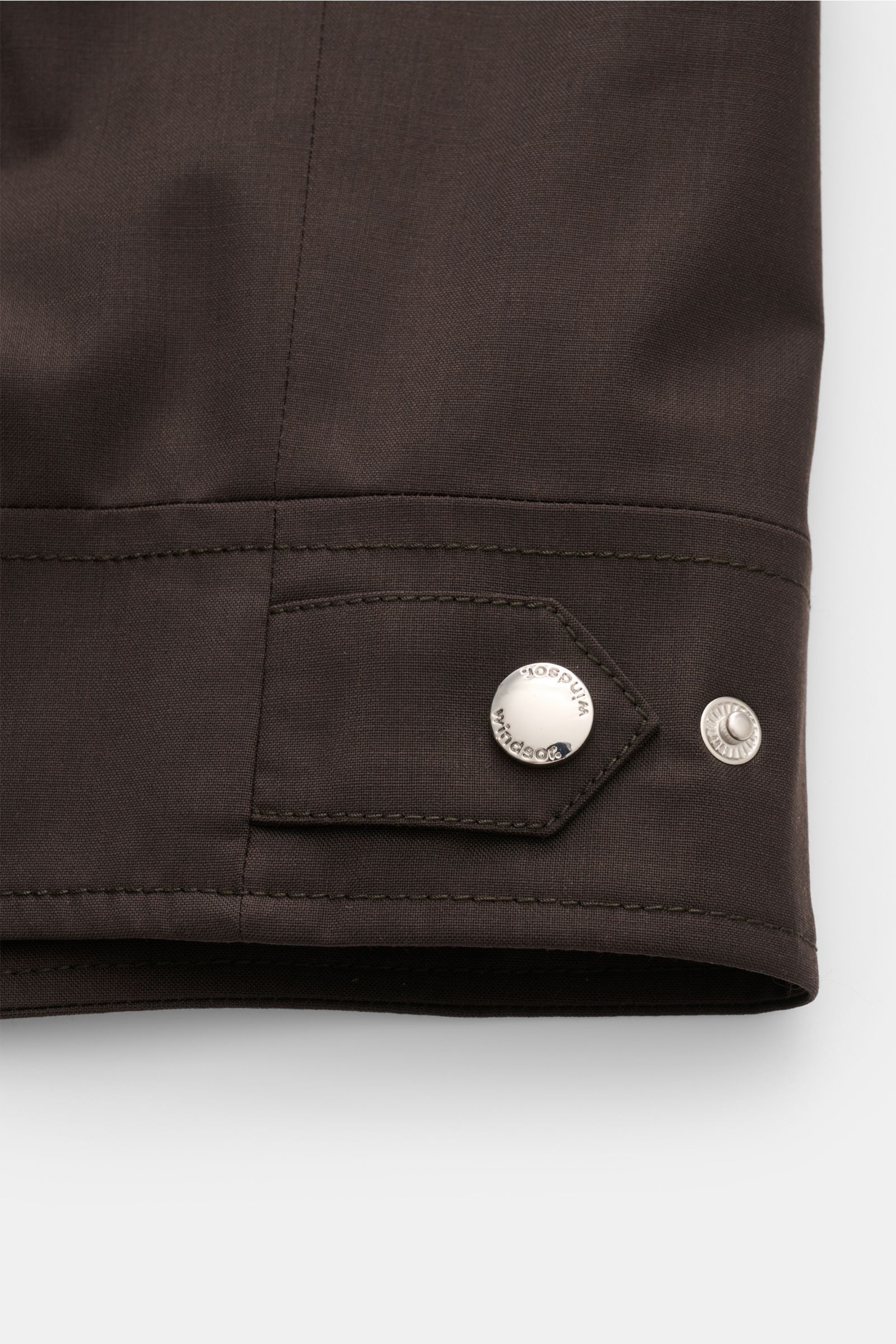 Close-up view of the sleeve cuff of the Windsor Blouson 'Attilio' dunkelbraun showing the adjustable button tab and fine stitching, crafted from lightweight pure new wool with a slim fit, robust two-way zipper, turn-down collar, diagonal zippered welt poc