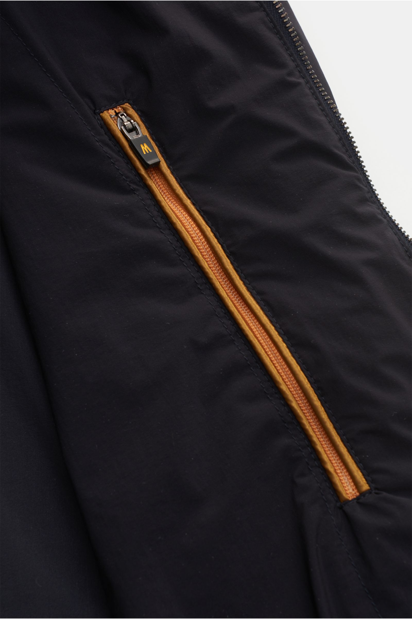 Close-up front view of the Moorer Blouson 'Giove' dark navy showing a detailed orange zipper pocket; Funktionale Outerwear mit zeitloser Eleganz von MOORER: Bereit für den Frühling sind wir mit dem ultraleichten Blouson 'Giove' aus hochwertiger Microfaser