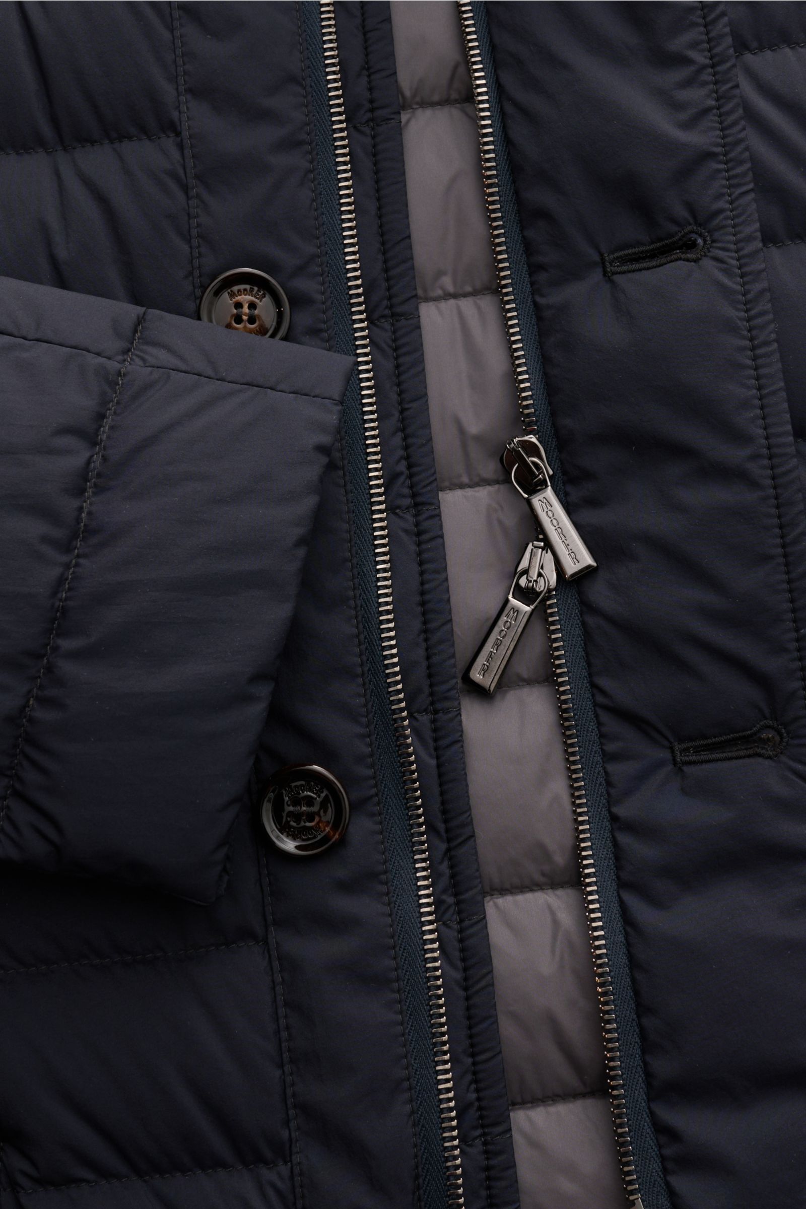 Close-up front view of the Moorer Down jacket 'Zavyer' navy showing quilted high-quality microfiber, two-way zip, buttons, and leather collar detail.

The elegant quilted jacket 'Zavyer' by MOORER will see you through the coldest months in style. Thank