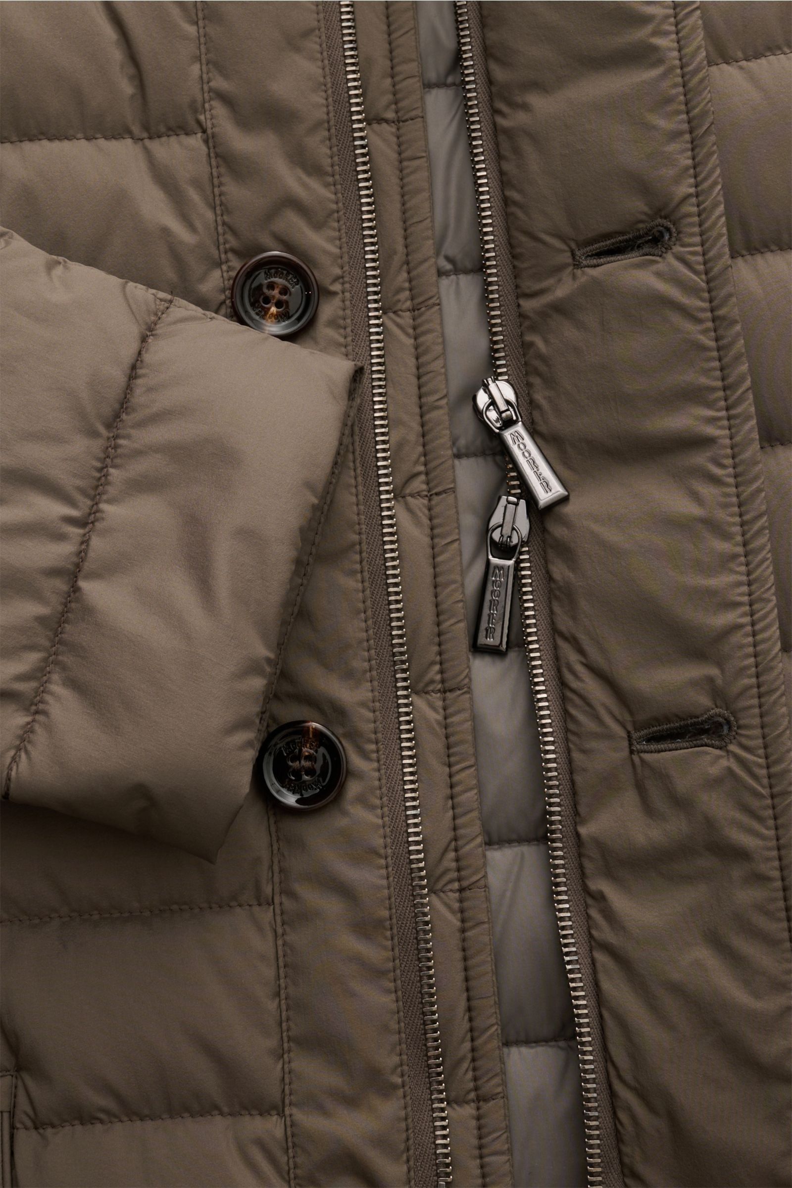 Close-up view of the Moorer Daunenjacke 'Zavyer' graugrün showing detailed stitching, buttons, and two-way zipper.

Description: Stilvoll durch die kühle Jahreszeit wird Sie die edle Steppjacke 'Zavyer' von MOORER begleiten, die dank leichter Daunenfül