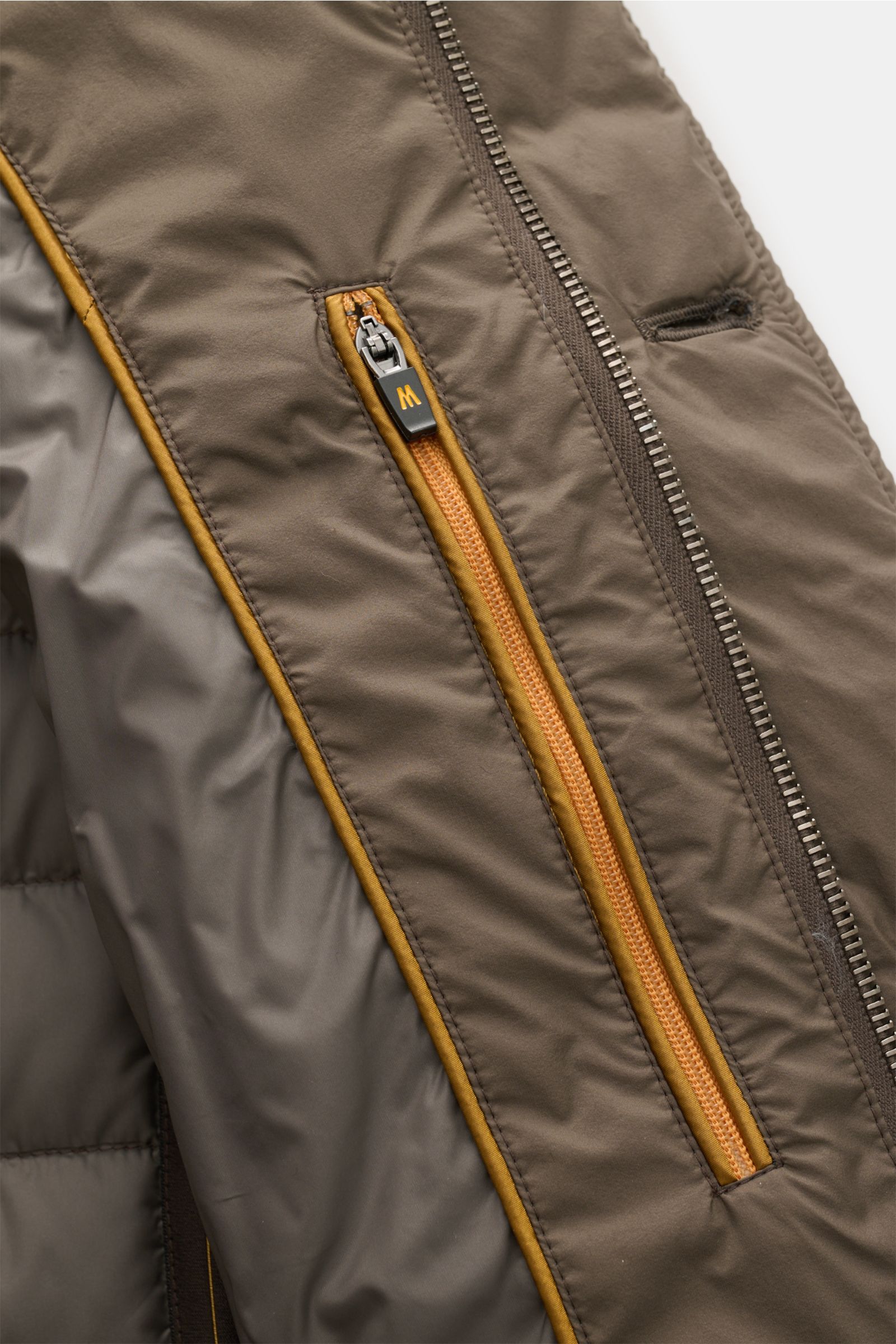 Close-up image from the inside perspective of the Moorer Daunenjacke 'Zavyer' graugrün, showing the high-quality microfaser with smooth grip, classic quilting, lightweight down filling, slim fit, leather collar detail, two-way zipper, wind flap with butto
