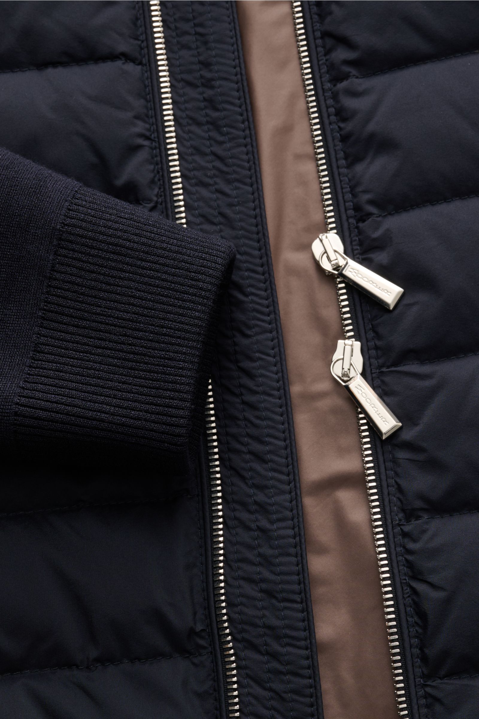 Nahaufnahme der Moorer Daunen-Strickjacke 'Duncan' navy von vorne, zeigt Strickbündchen, zwei-Wege-Reißverschluss und gesteppte Daunenfront.