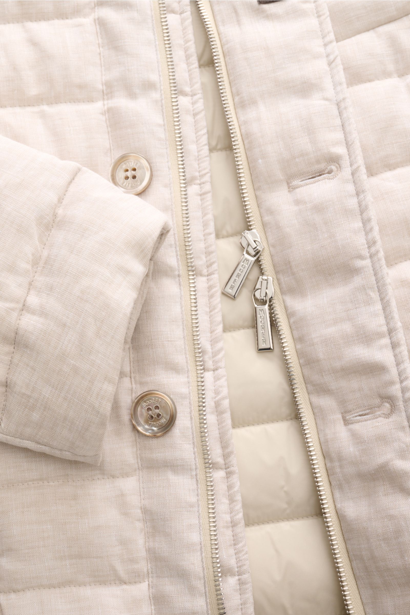 Close-up front view of the Moorer Down jacket 'Zavyer' beige mottled, showing quilted pure linen fabric, leather-collared sleeve, buttons, two-way zip, and lightweight down lining. The elegant quilted jacket 'Zavyer' by MOORER will see you through the tra