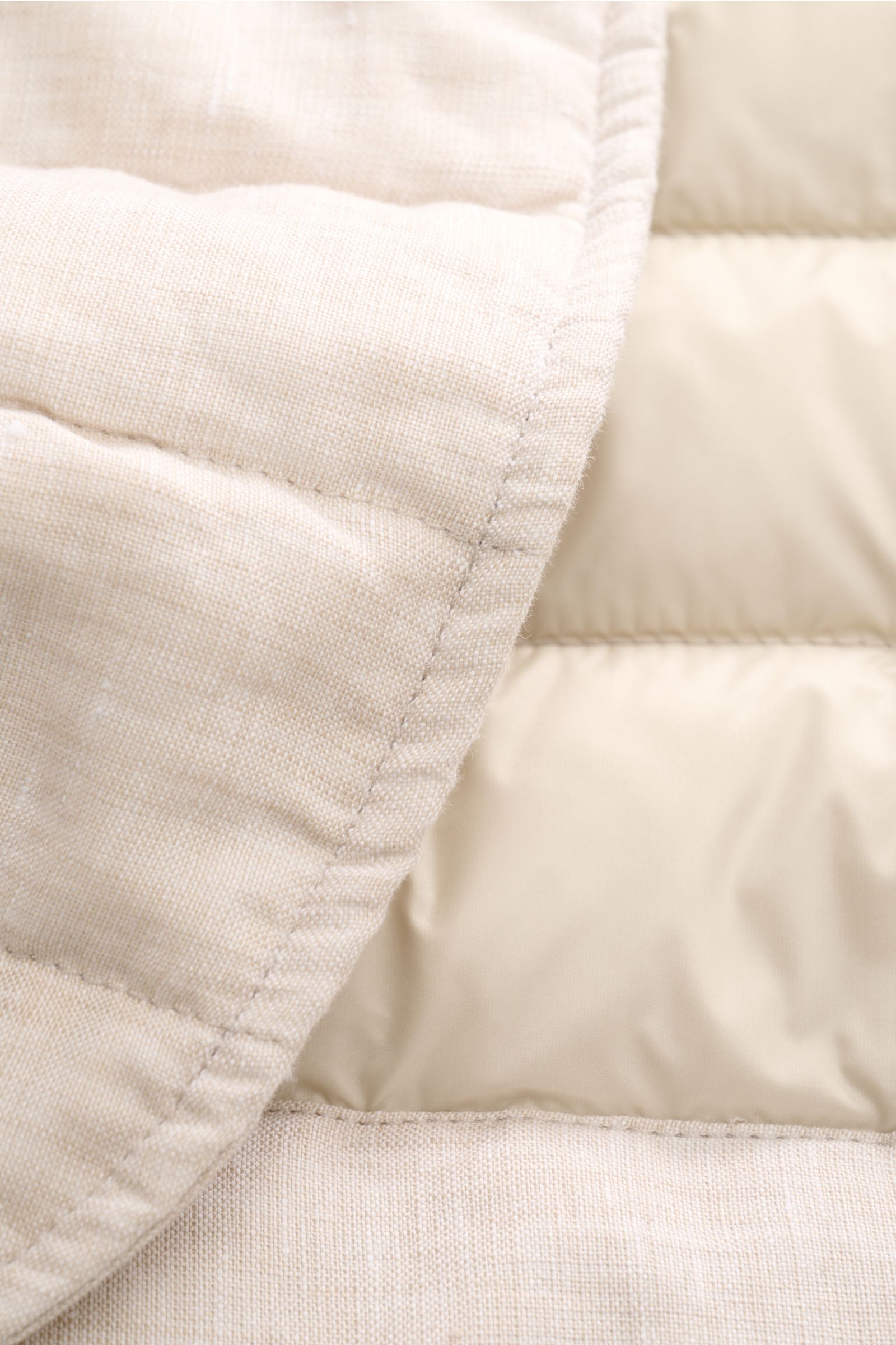 Nahaufnahme der beige melierten Moorer Daunenjacke 'Zavyer' mit Steppnähten, Leinenstoff und leichter Daunenfüllung, Detail von innen und außen.