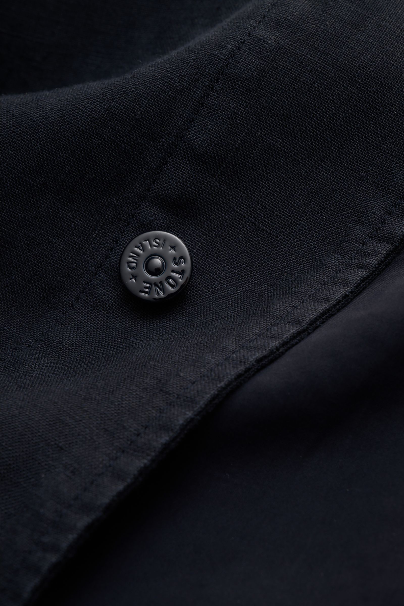 Close-up front detail of Stone Island Jacket 'Ghost Piece' navy showing linen blend fabric, concealed button placket, and tonal snap button from a top-down angle. Springtime meets casual: This STONE ISLAND jacket from the 'Ghost' Capsule has been made fro