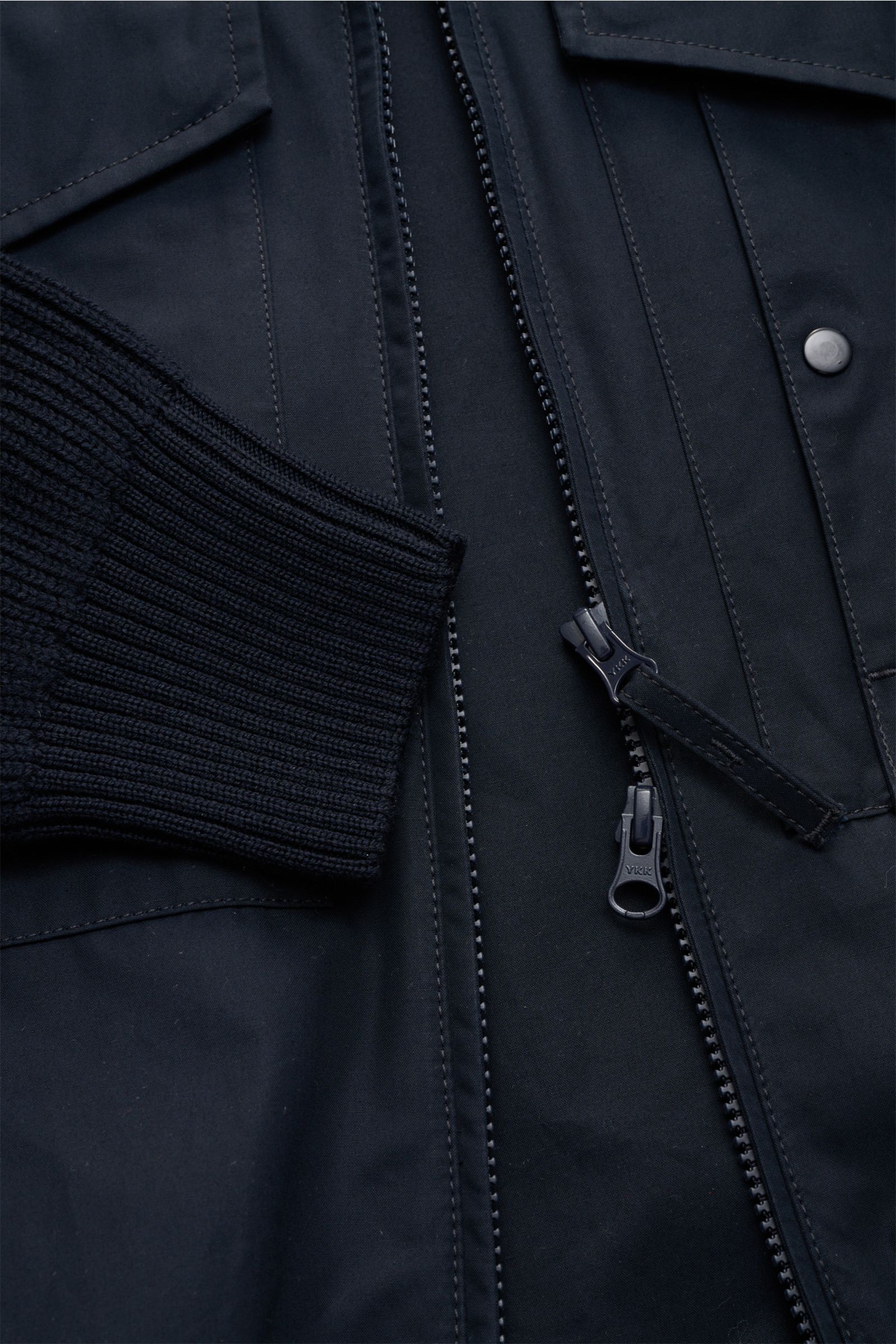 Nahaufnahme des Stone Island Blouson 'Ghost Piece' navy aus der Ghost Collection, zeigt windabweisenden Baumwoll-Corpus, Strickbündchen, zwei-Wege-Reißverschluss und tonales Badge am Oberarm.